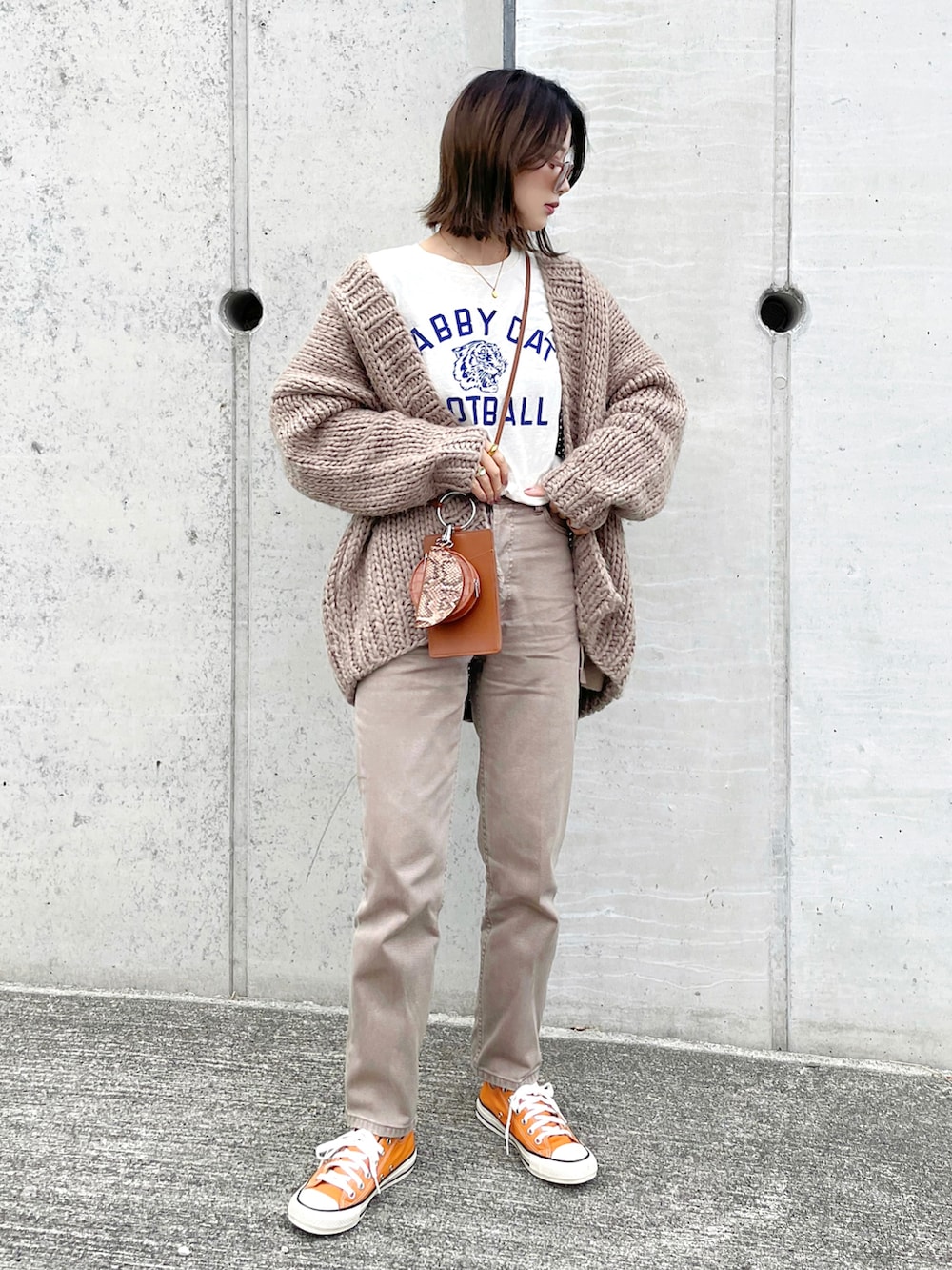 ブラウン系のデニムパンツ、ホワイト系のTシャツ/カットソー、ブラウン系のショルダーバッグを着用したレディースの冬コーディネートの2枚目の写真