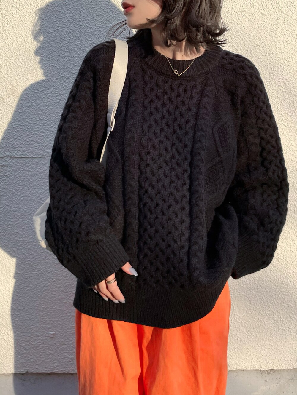 オレンジ系のその他パンツ、ブラック系のスニーカー、ブラック系のニット/セーターを着用したレディースの秋コーディネートの2枚目の写真