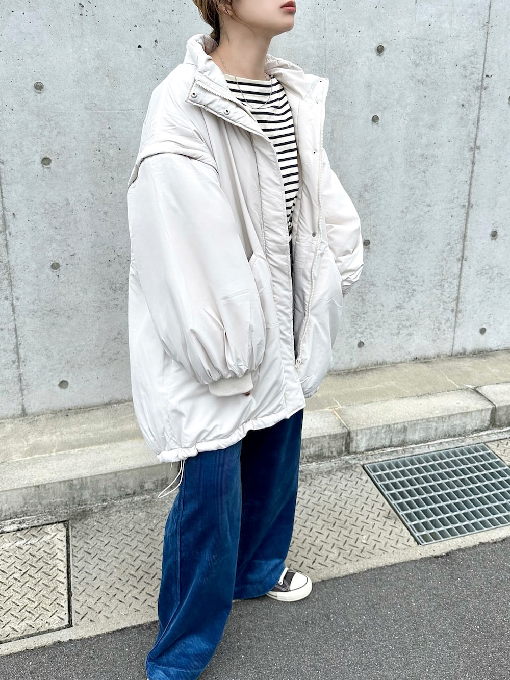 ホワイト系のダウンジャケット/コート、ブルー系のパンツ、ブラック系のスニーカーを着用したレディースの秋コーディネートの3枚目の写真