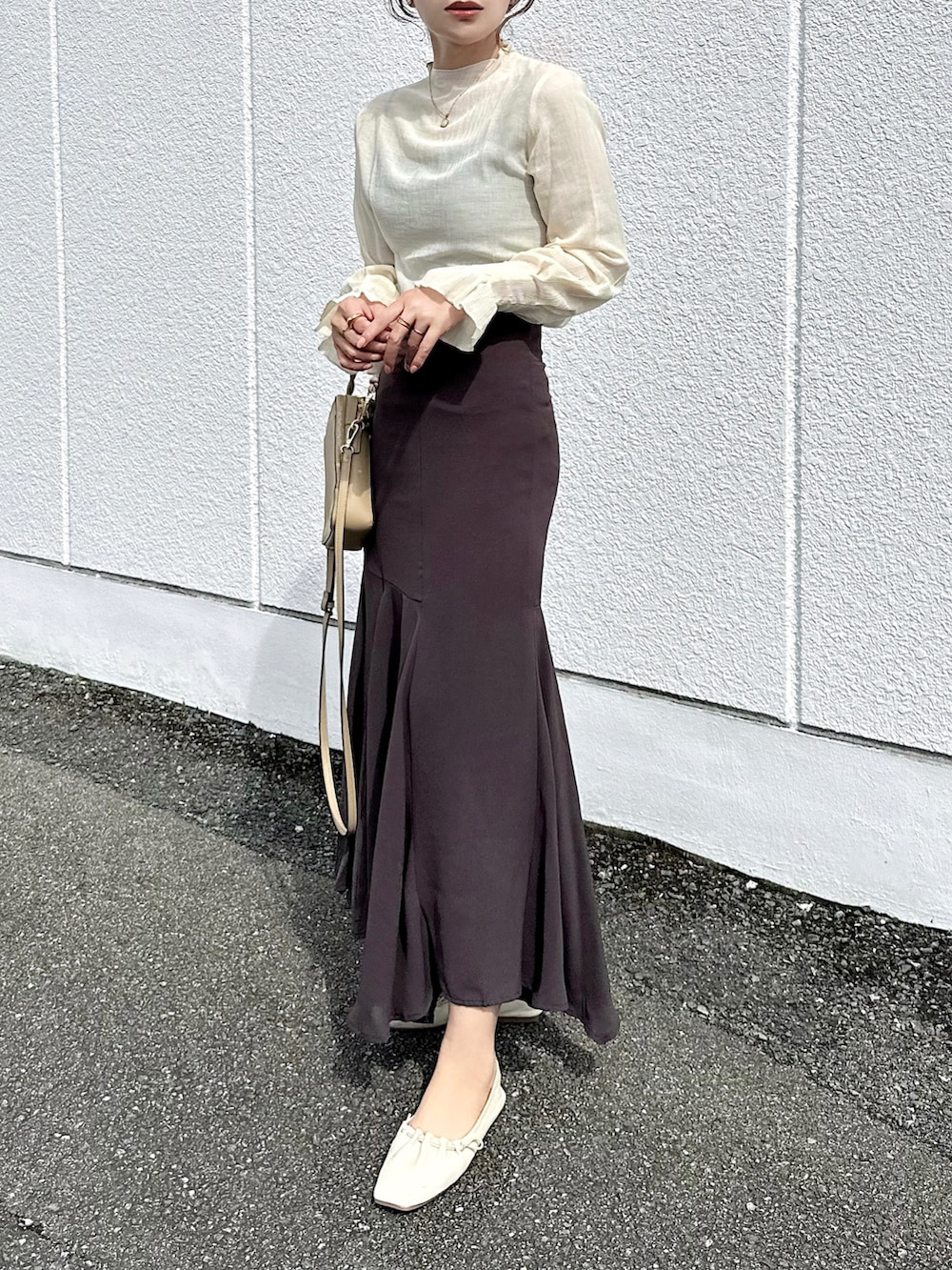 ブラウン系のスカート、ベージュ系のTシャツ/カットソー、ベージュ系のバッグを着用したレディースの秋コーディネートの3枚目の写真