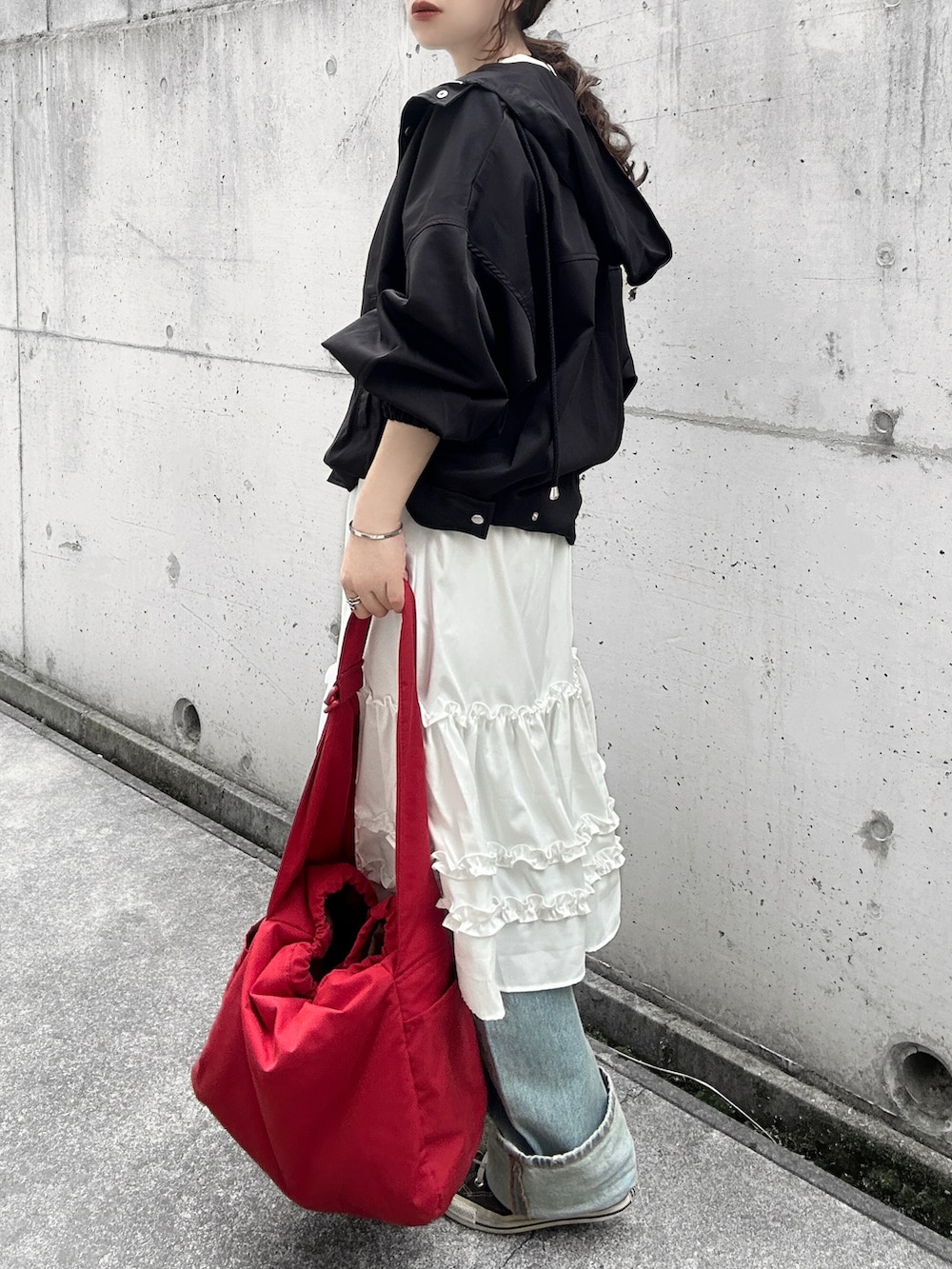 ブラック系のマウンテンパーカー、ホワイト系のスカート、ホワイト系のTシャツ/カットソーを着用したレディースの春コーディネートの3枚目の写真