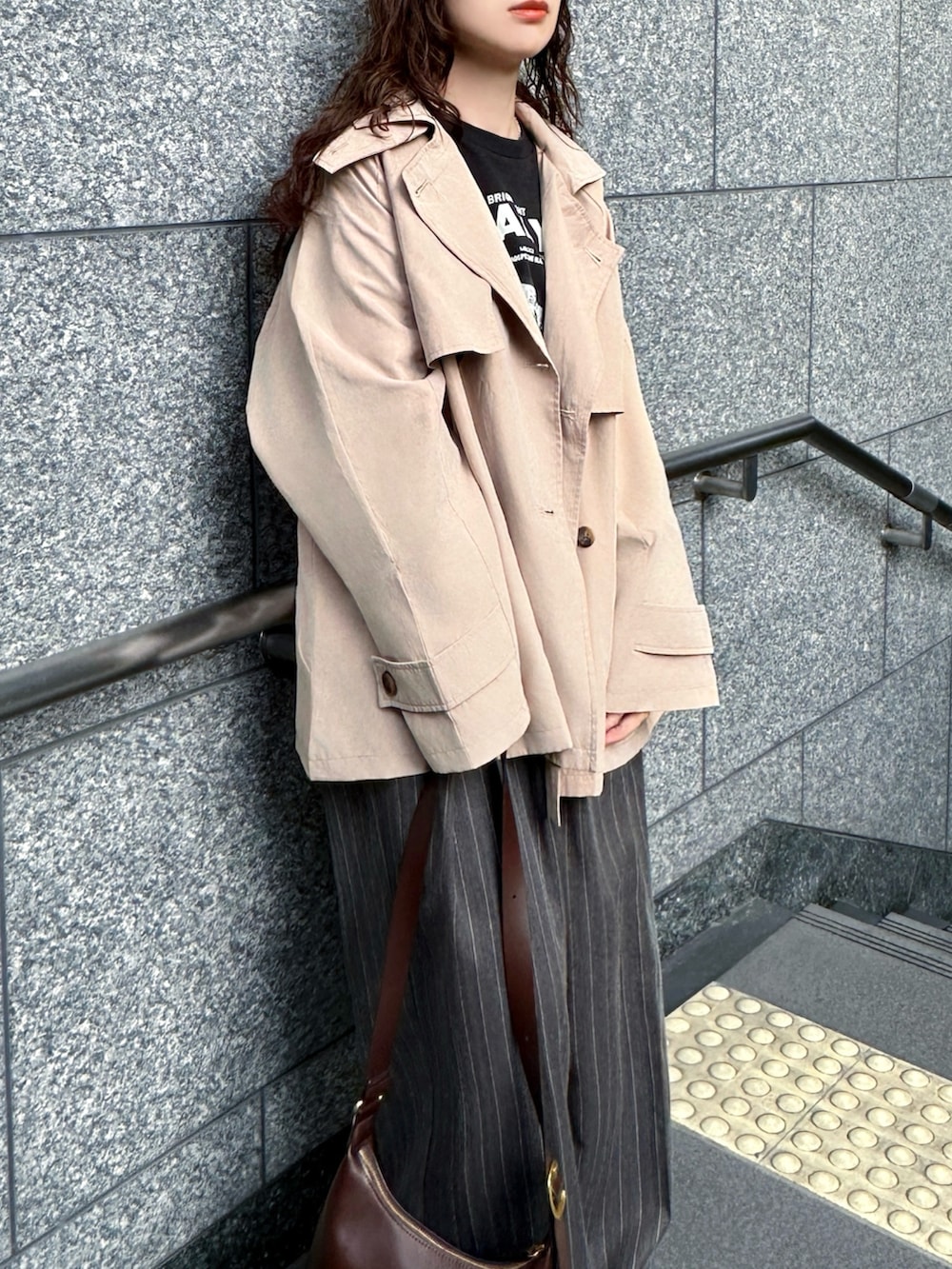 ベージュ系のトレンチコート、ブラック系のTシャツ/カットソー、グレー系のその他パンツを着用したレディースの春コーディネートの2枚目の写真