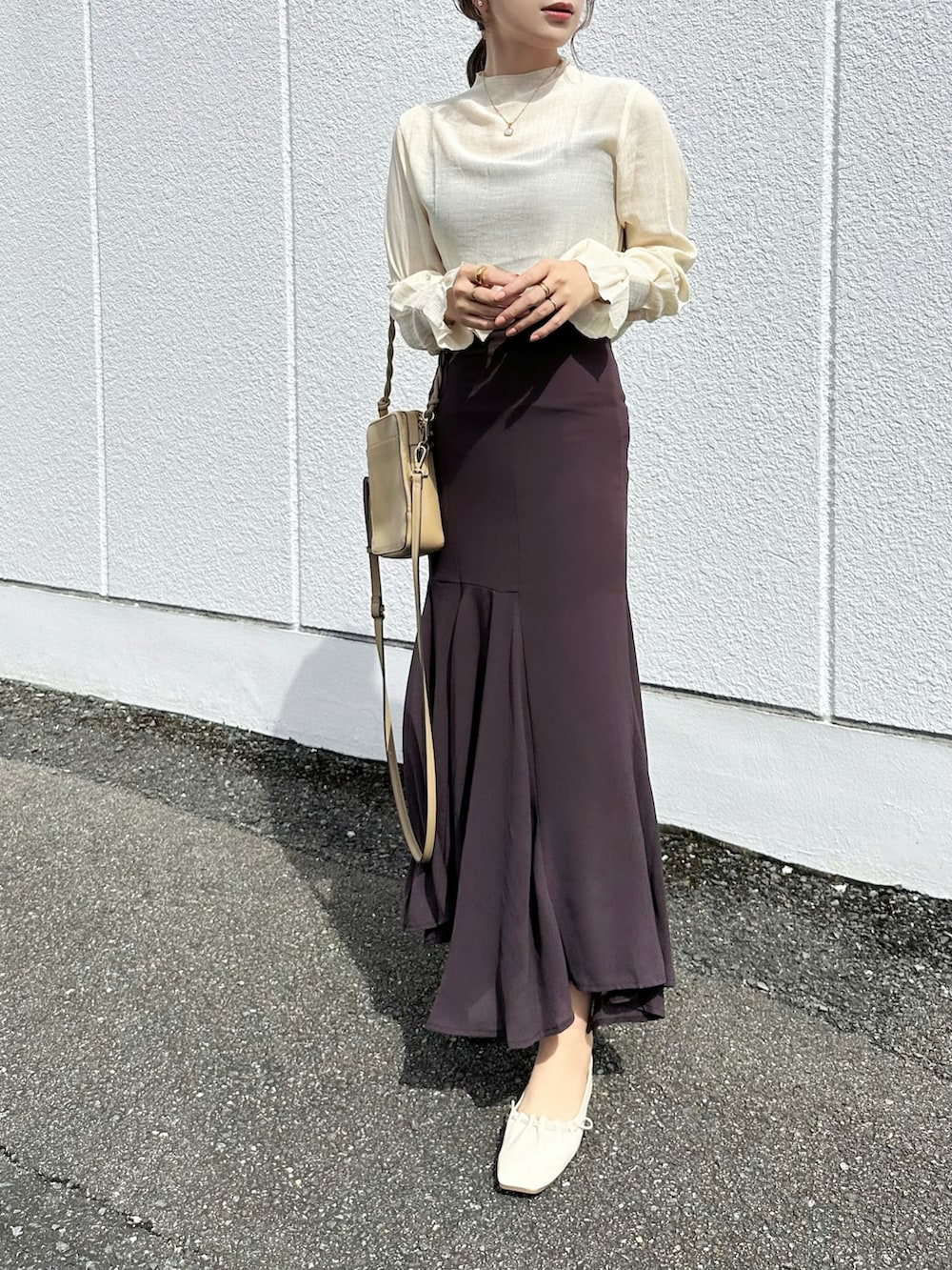 ブラウン系のスカート、ベージュ系のTシャツ/カットソー、ベージュ系のバッグを着用したレディースの秋コーディネートの2枚目の写真