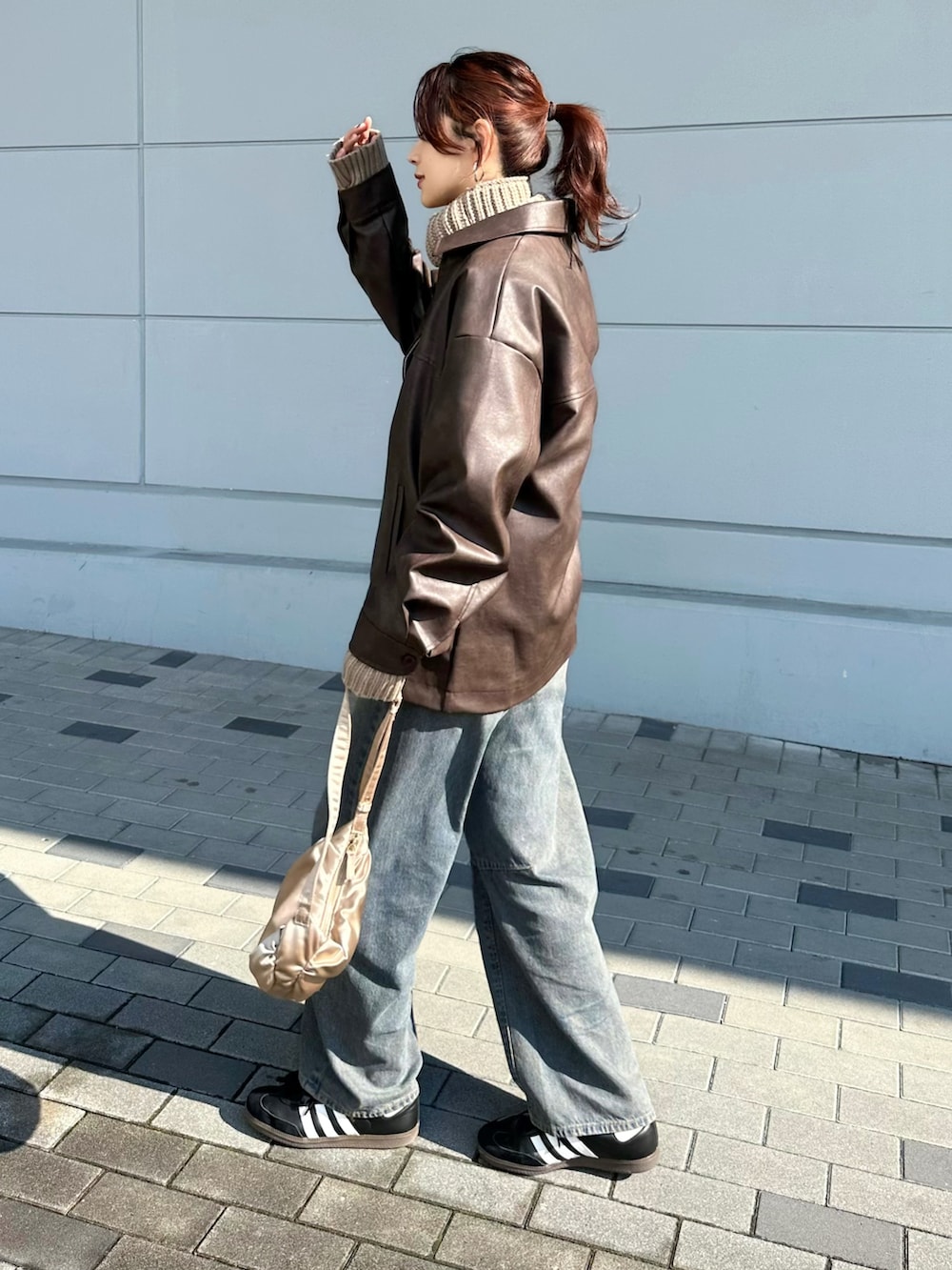 ブラウン系のブルゾン、ベージュ系のニット/セーター、ブルー系のデニムパンツを着用したレディースの冬コーディネートの4枚目の写真