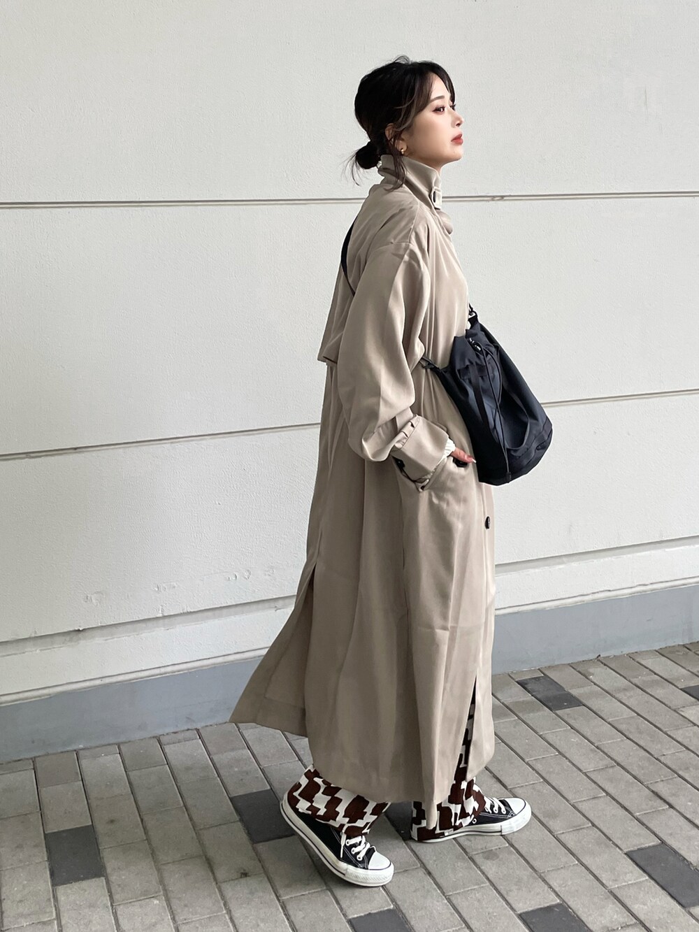 ベージュ系のトレンチコート、ブラウン系のパンツ、ブラック系のバッグを着用したレディースの冬コーディネートの3枚目の写真