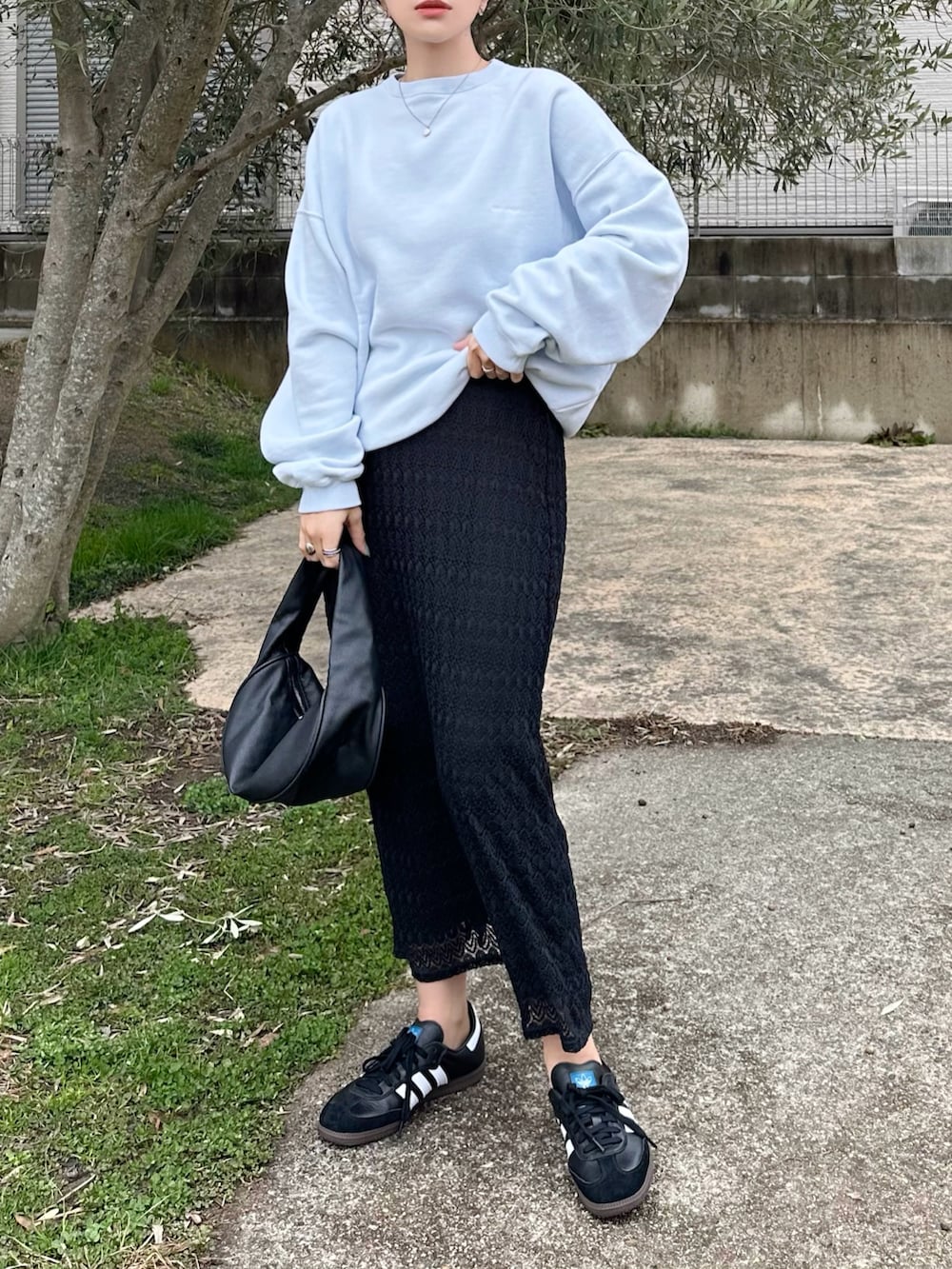 ブルー系のスウェット、ブラック系のハンドバッグ、ブラック系のスニーカーを着用したレディースの春コーディネートの2枚目の写真