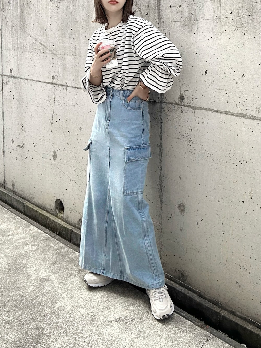 ホワイト系のTシャツ/カットソー、ブルー系のデニムスカート、ベージュ系のスニーカーを着用したレディースの春コーディネートの3枚目の写真