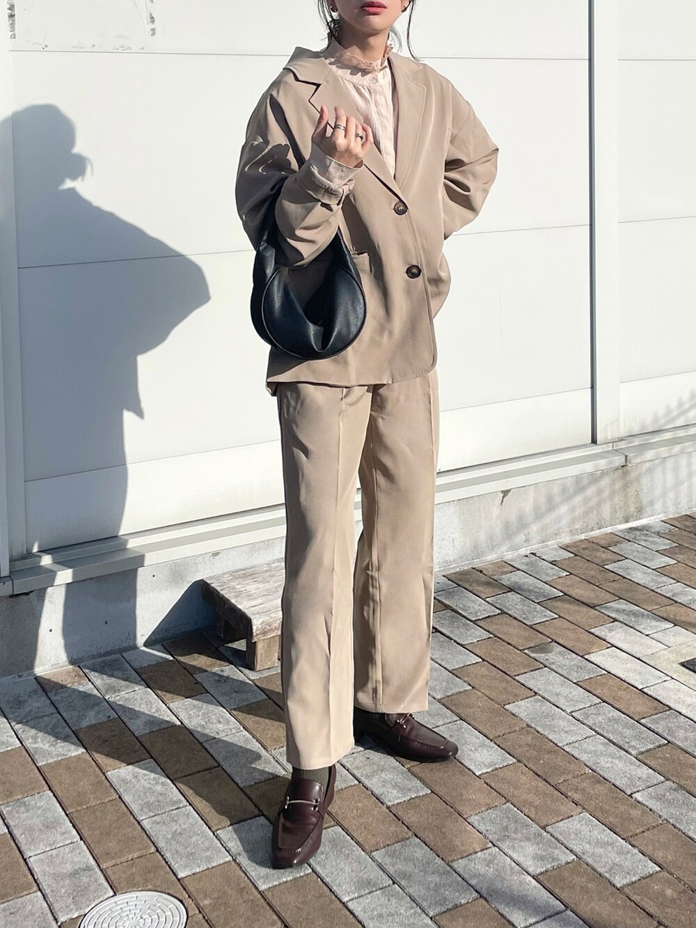 ベージュ系のセットアップ、ベージュ系のシャツ/ブラウス、ブラック系のハンドバッグを着用したレディースの冬コーディネートの2枚目の写真