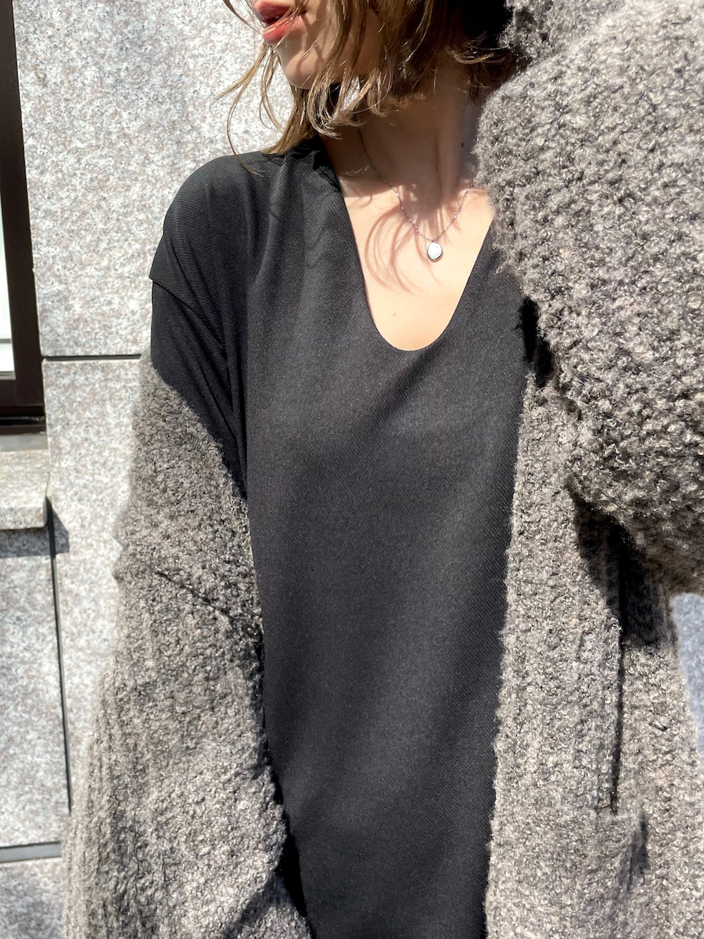 ブラック系のワンピース、ベージュ系のカーディガン/ボレロ、ブラウン系のバッグを着用したレディースの秋コーディネートの2枚目の写真