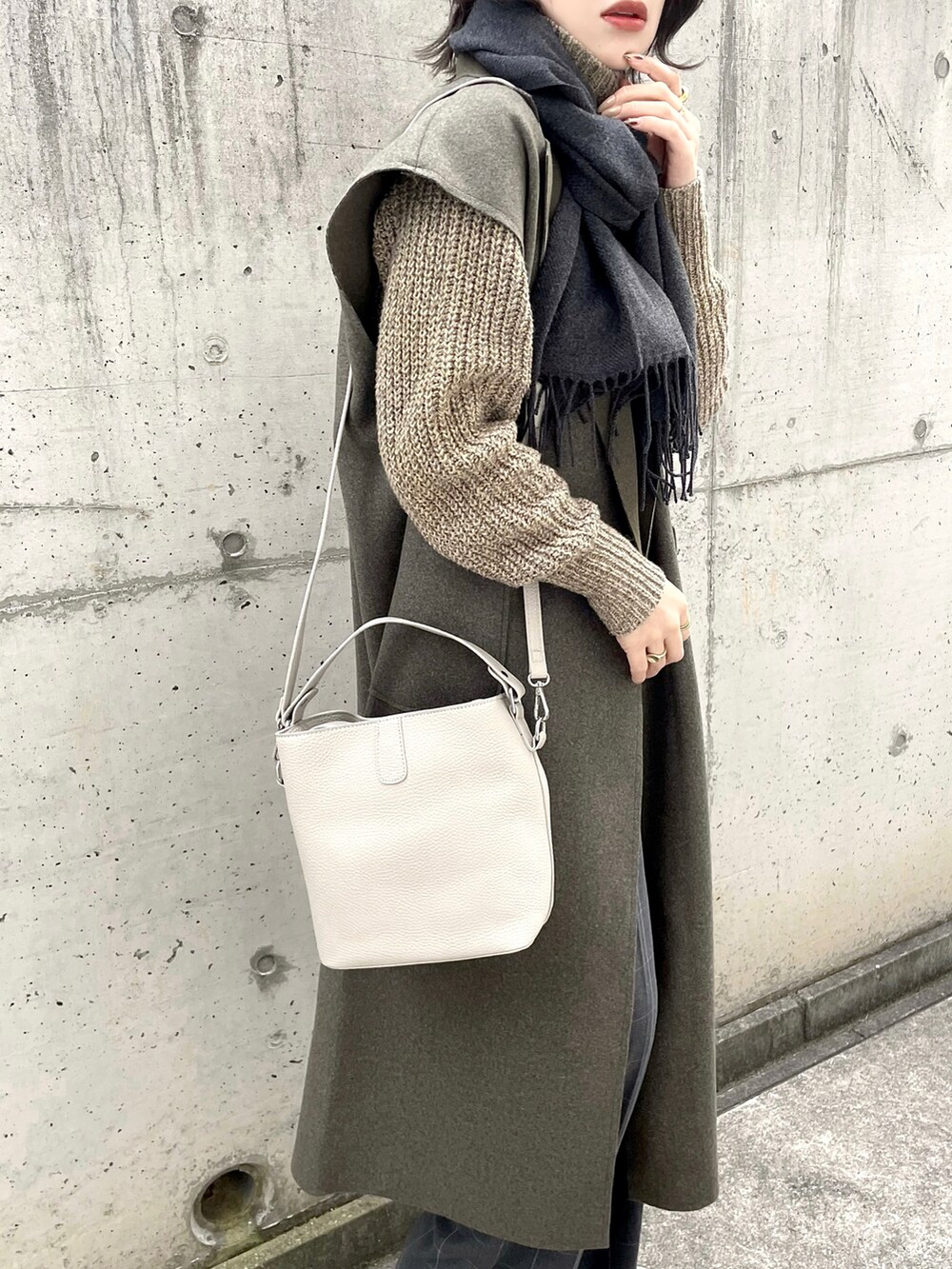 ベージュ系のハンドバッグ、ブラウン系のベスト、グレー系のパンツを着用したレディースの冬コーディネートの4枚目の写真