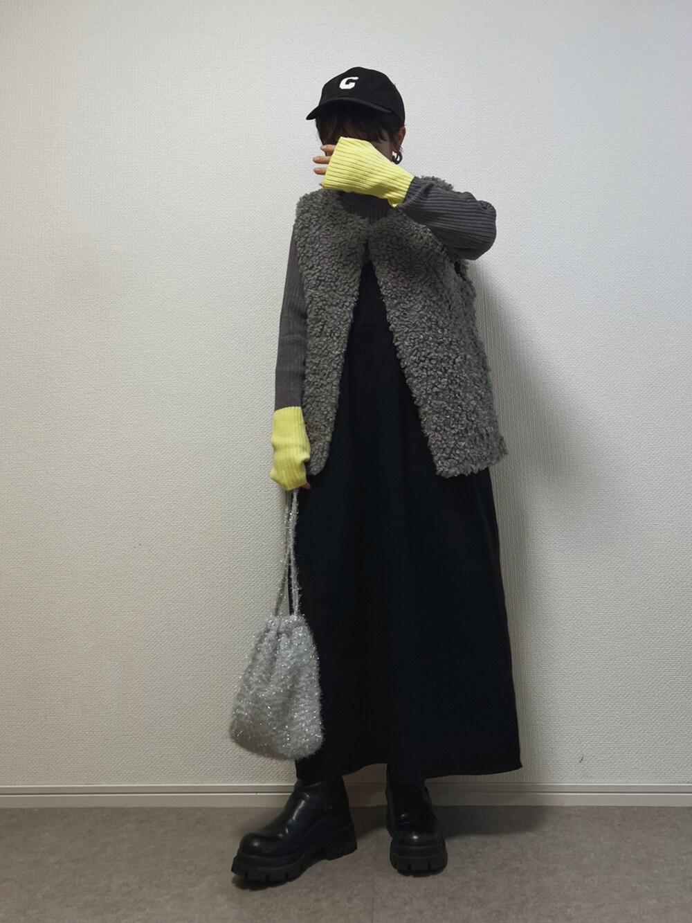 グレー系のニット/セーター、シルバー系のショルダーバッグ、ブラック系のジャンパースカートを着用したレディースの冬コーディネートの2枚目の写真
