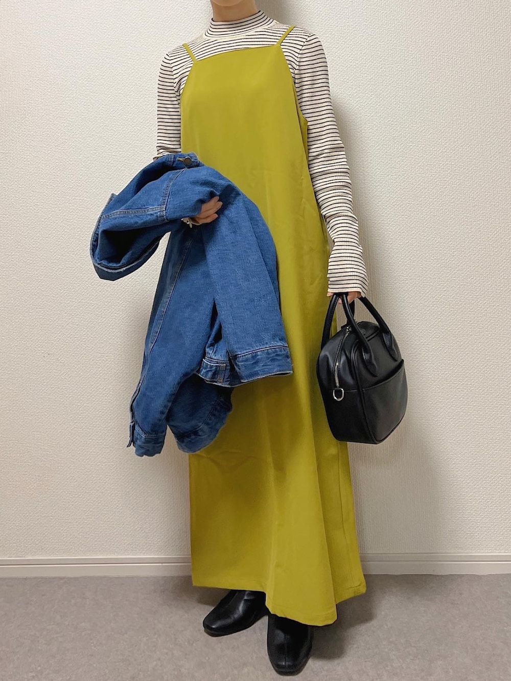 ブルー系のデニムジャケット、ブラック系のショルダーバッグ、ブラック系のブーツを着用したレディースの冬コーディネートの2枚目の写真