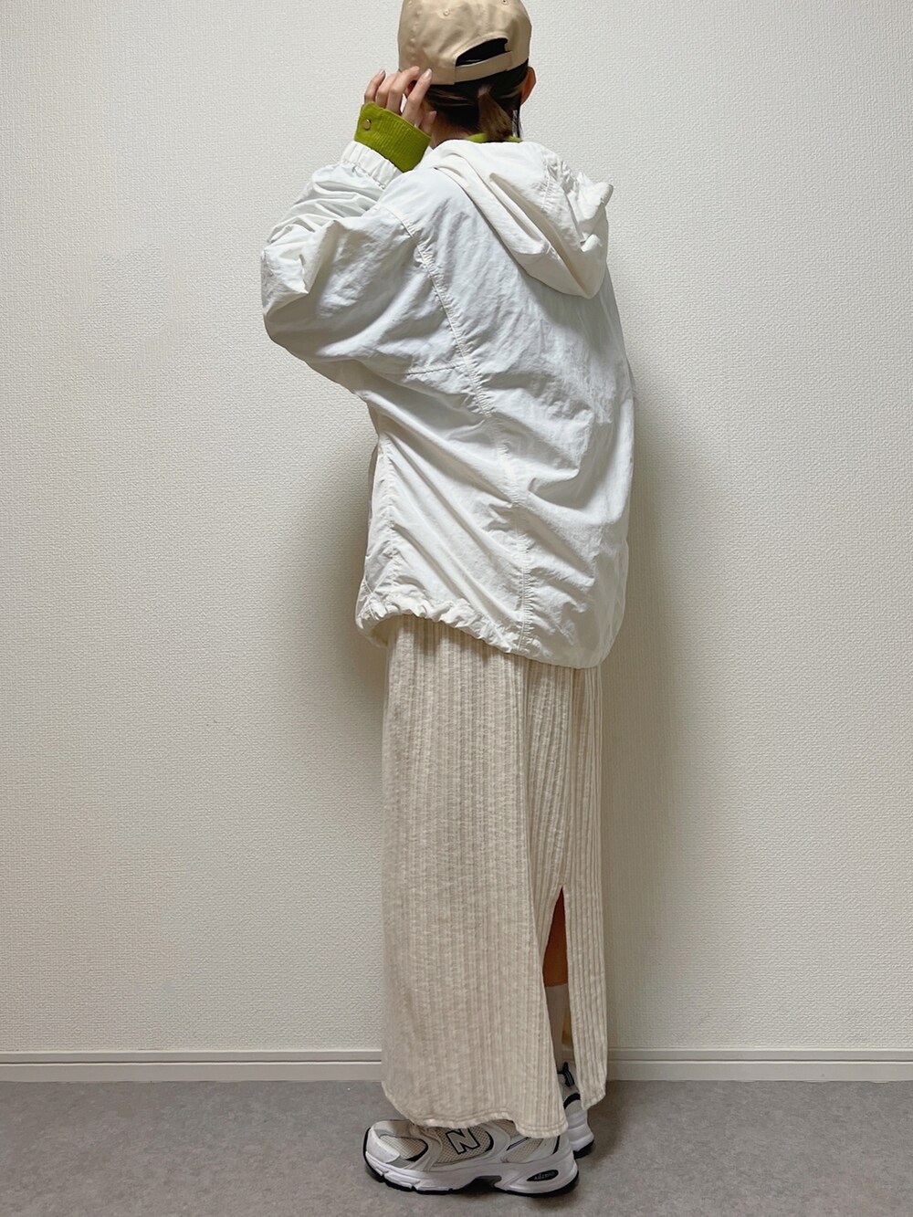 グリーン系のニット/セーター、ホワイト系のスカート、ホワイト系のスニーカーを着用したレディースの冬コーディネートの2枚目の写真