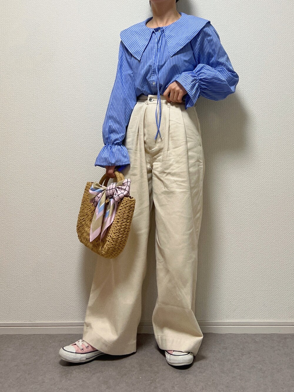 ホワイト系のデニムパンツ、ベージュ系のかごバッグ、ピンク系のスニーカーを着用したレディースの春コーディネートの2枚目の写真