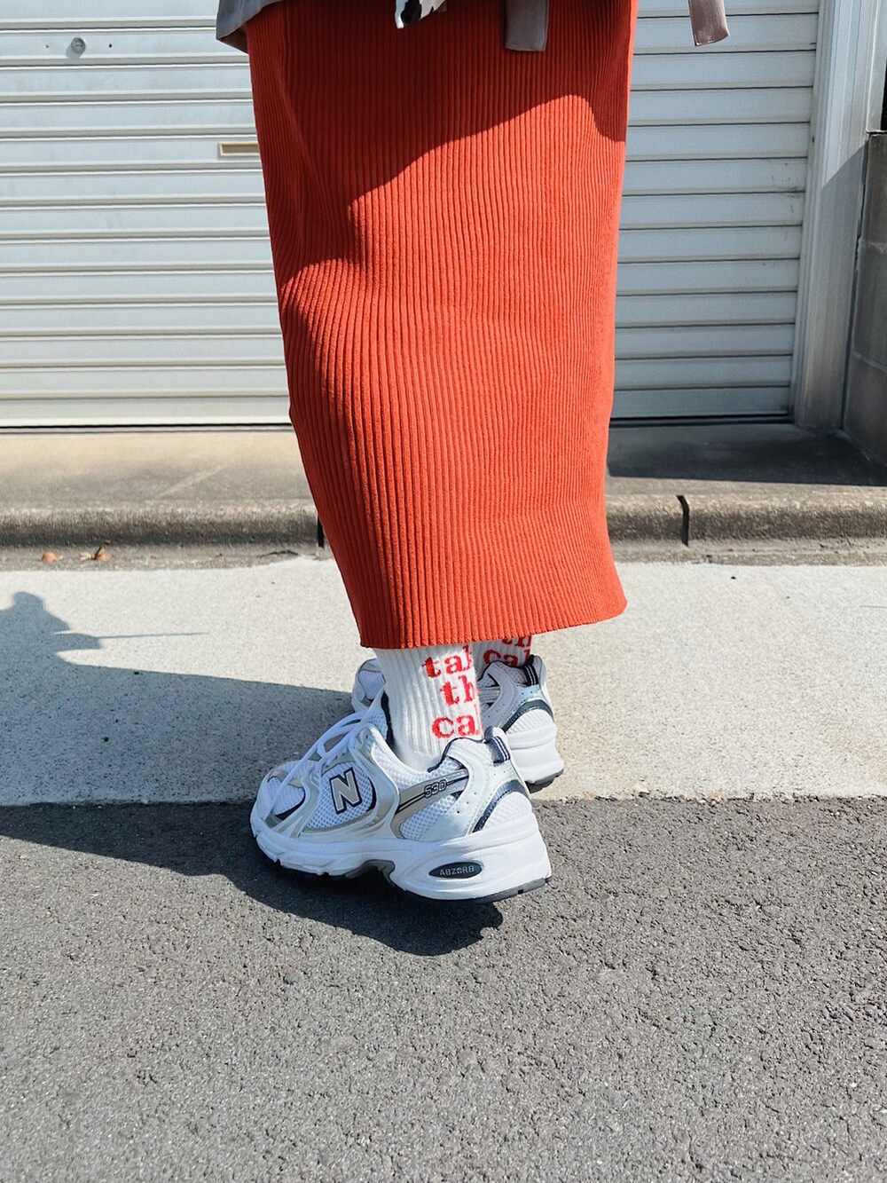 ホワイト系のTシャツ/カットソー、ブラック系のスカート、ホワイト系のスニーカーを着用したレディースの春コーディネートの2枚目の写真