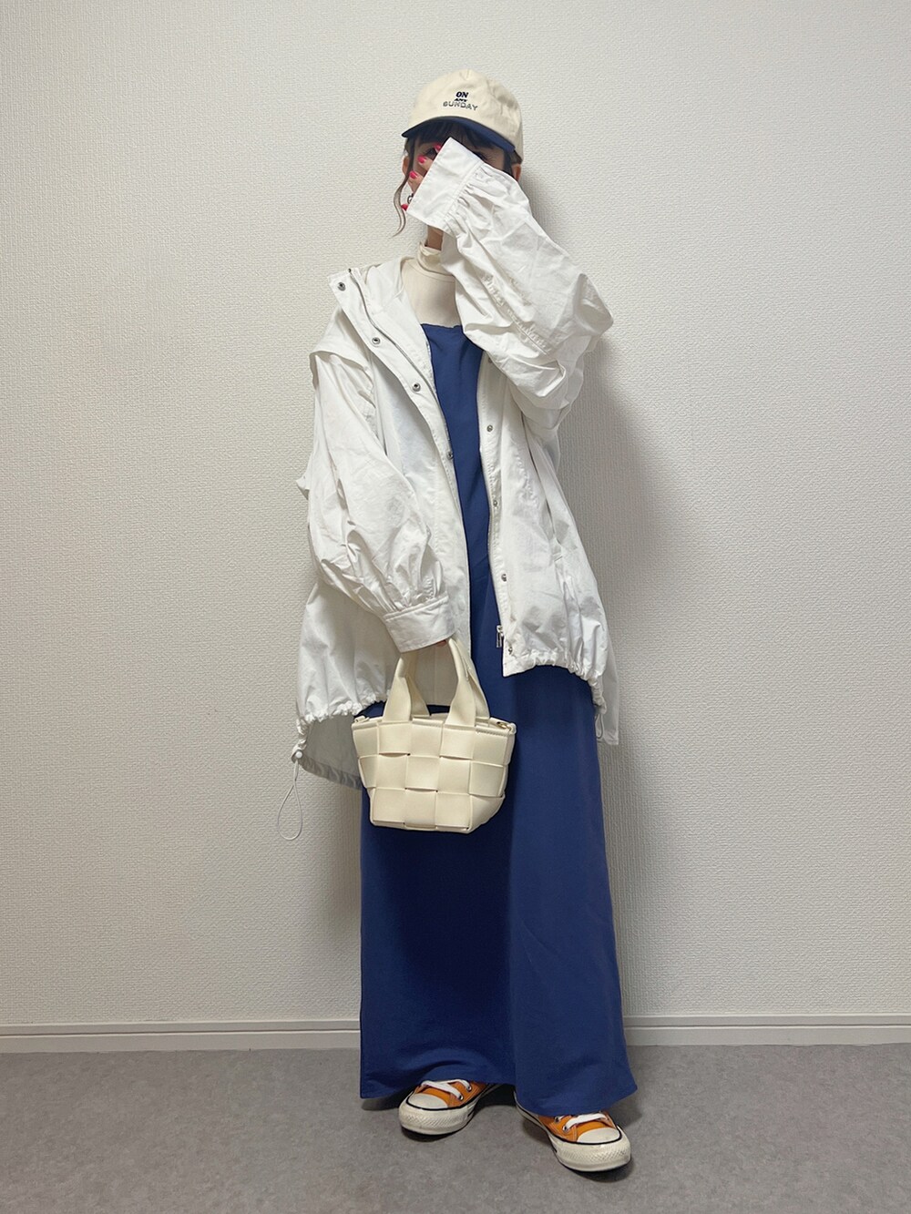 オレンジ系のスニーカー、ブルー系のワンピース、ホワイト系のブルゾンを着用したレディースの春コーディネートの2枚目の写真