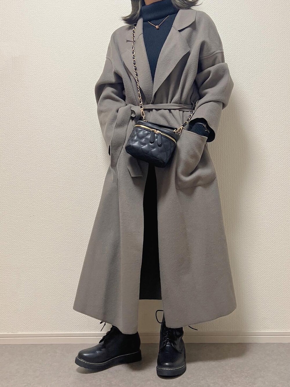 ブラック系のショルダーバッグ、ブラック系のブーツを着用したレディースの冬コーディネートの2枚目の写真