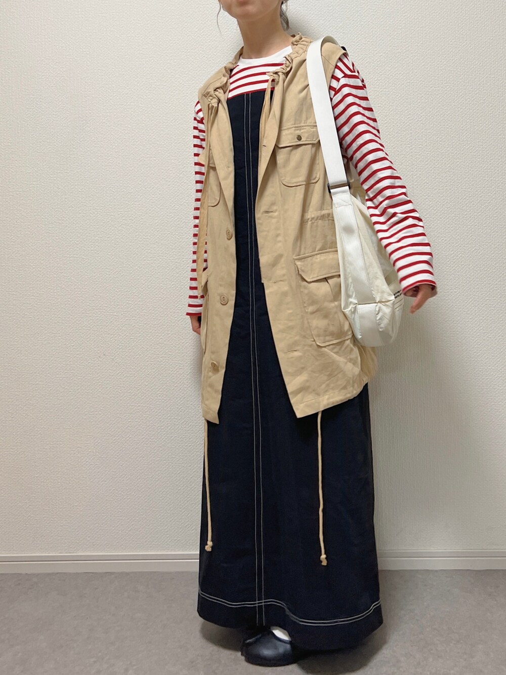 ベージュ系のベスト、ホワイト系のショルダーバッグ、ブラック系のバレエシューズを着用したレディースの春コーディネートの2枚目の写真