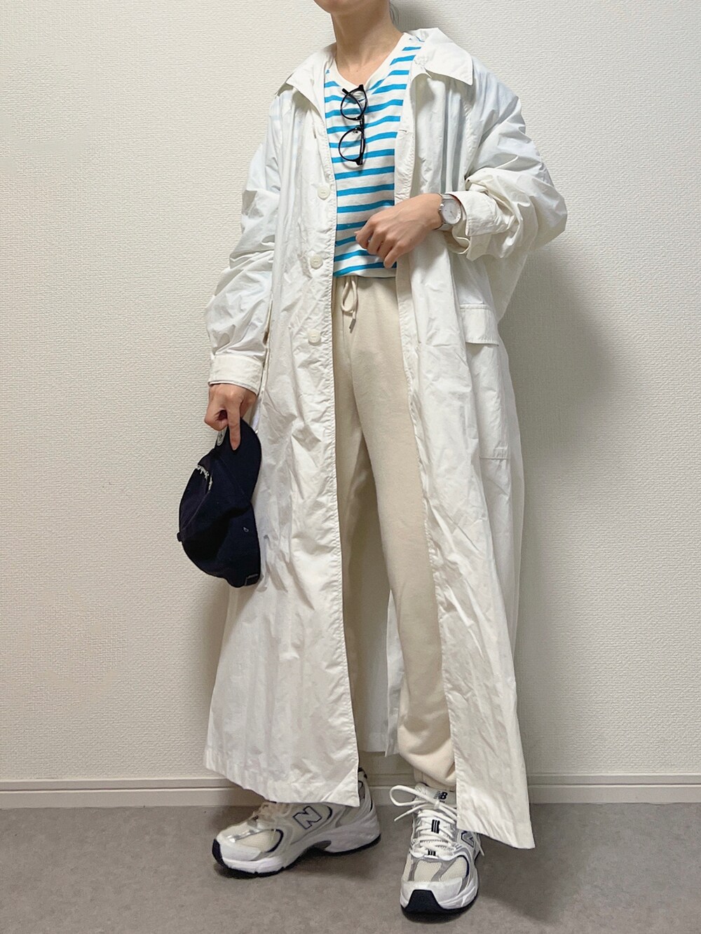 ブルー系のTシャツ/カットソー、ホワイト系のステンカラーコート、ホワイト系のスニーカーを着用したレディースの春コーディネートの2枚目の写真