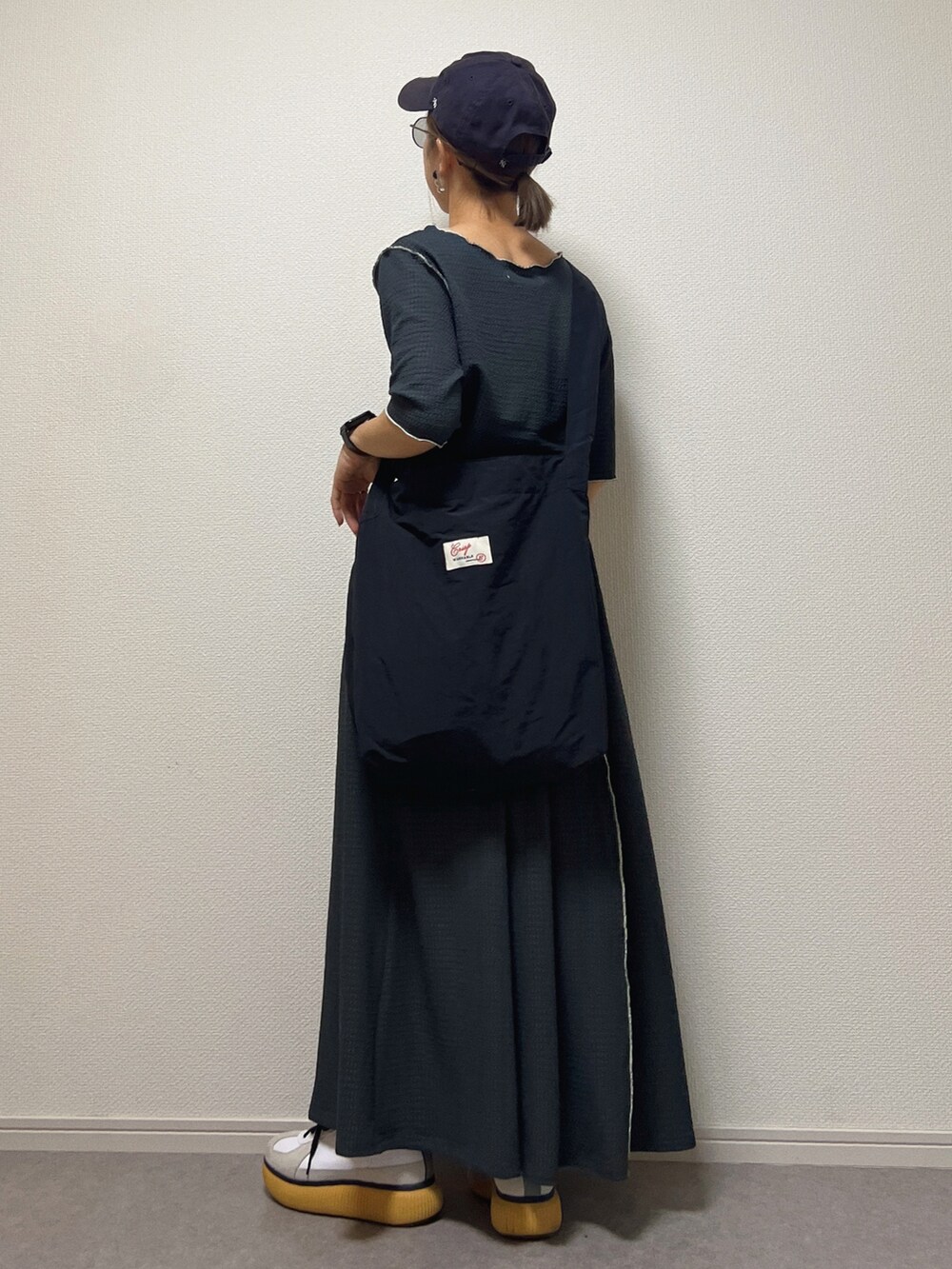 グレー系のTシャツ/カットソー、グレー系のスカート、ブラック系のショルダーバッグを着用したレディースの春コーディネートの2枚目の写真