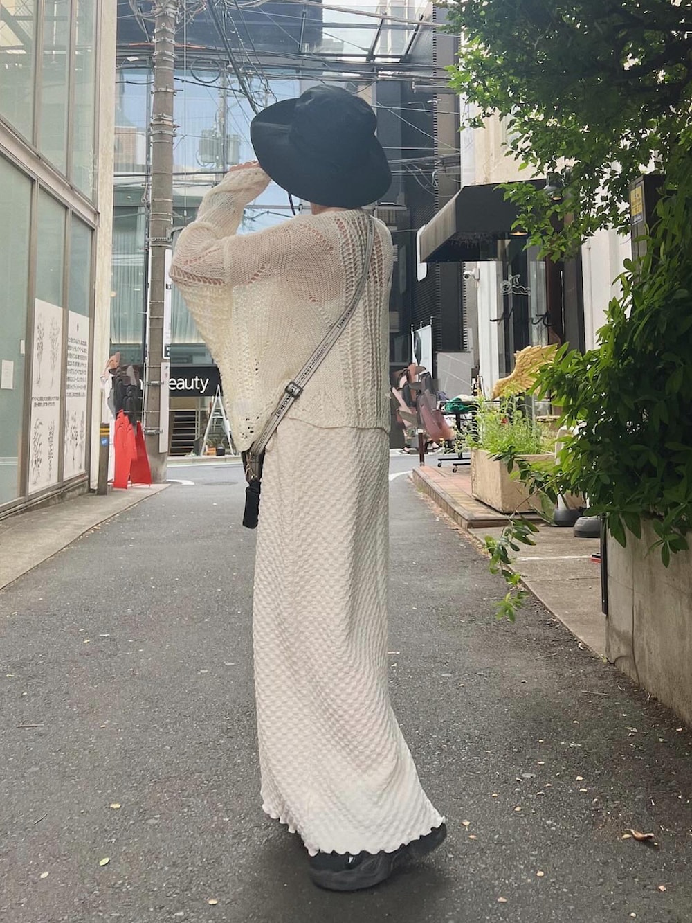 ブラック系のショルダーバッグ、ホワイト系のワンピース、ホワイト系のサングラスを着用したレディースの春コーディネートの2枚目の写真