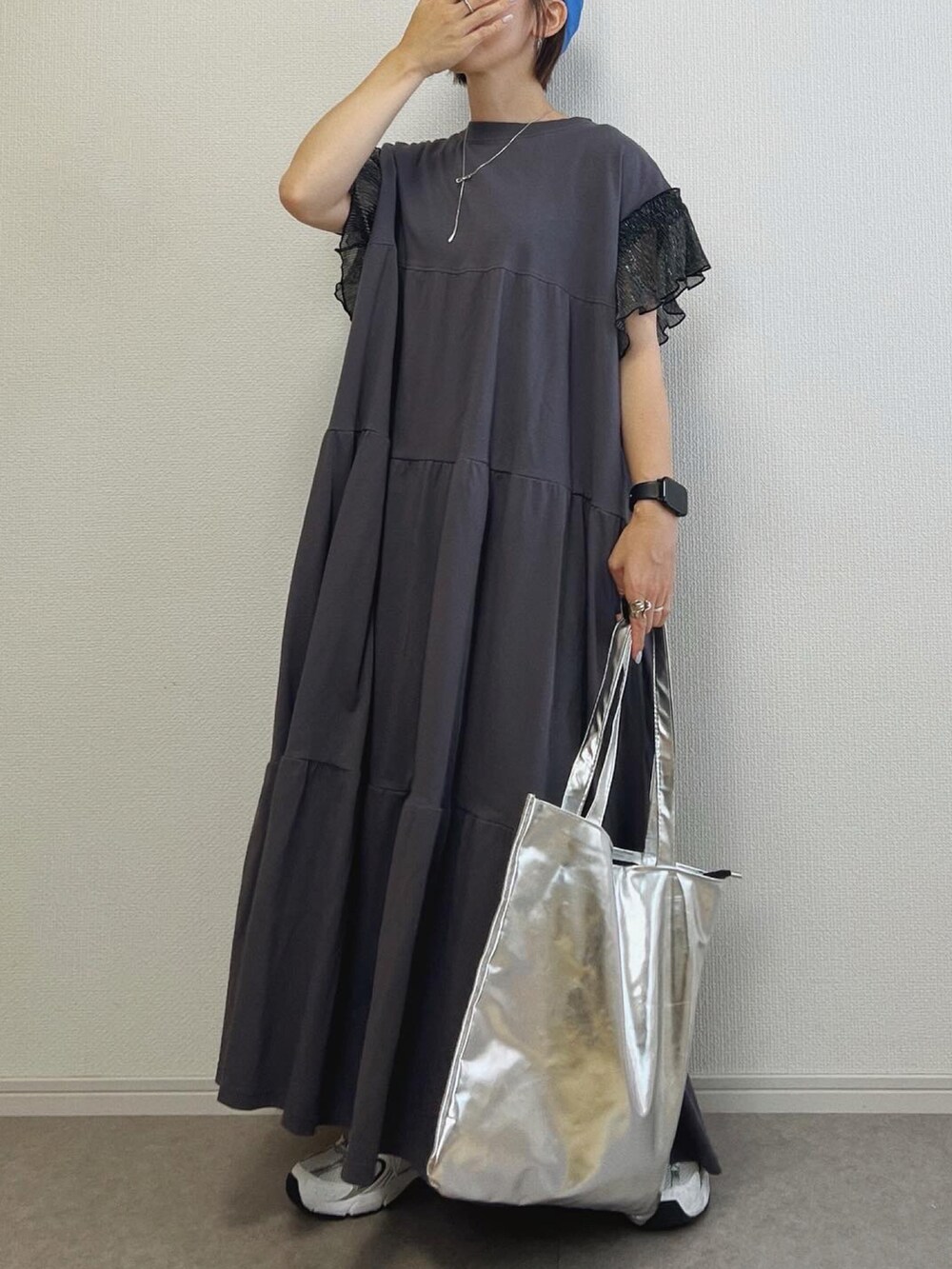 ブラック系のワンピース、シルバー系のトートバッグ、シルバー系のスニーカーを着用したレディースの夏コーディネートの2枚目の写真