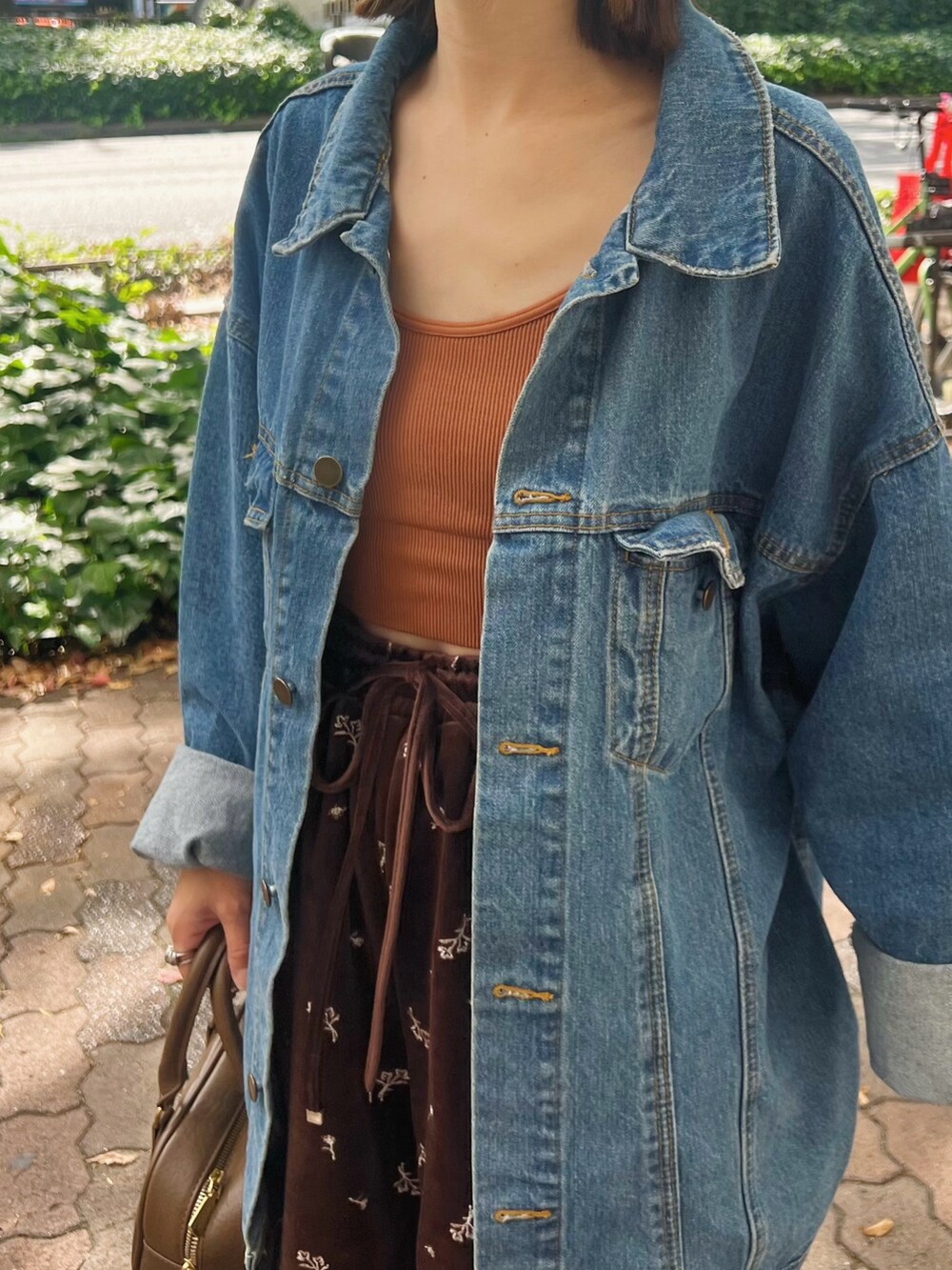 ホワイト系のスニーカー、ブルー系のデニムジャケット、ブラウン系のボストンバッグを着用したレディースの秋コーディネートの3枚目の写真