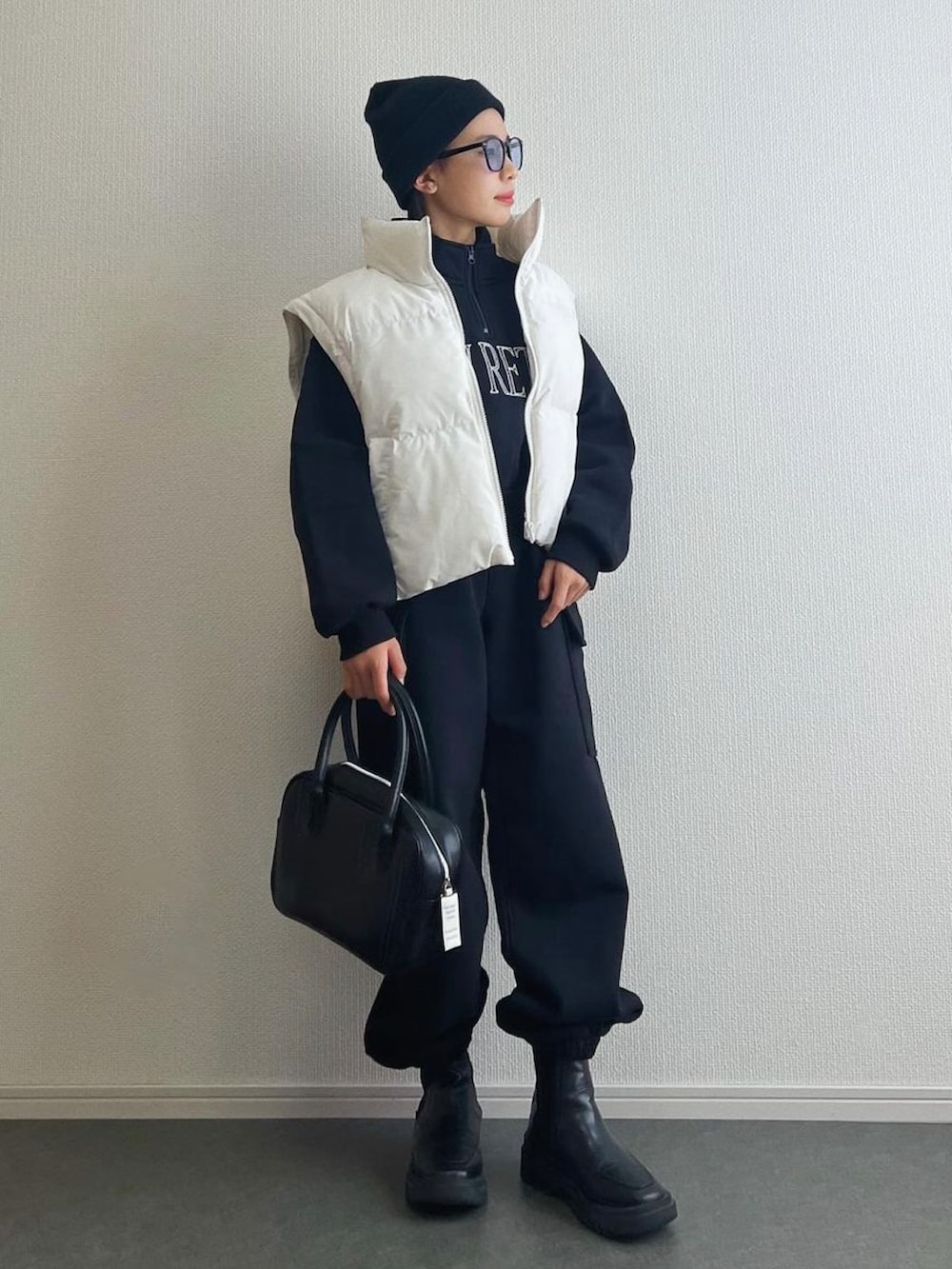 ホワイト系のジャケット/アウター、ブラック系のボストンバッグ、ブラック系のブーツを着用したキッズの秋コーディネートの2枚目の写真