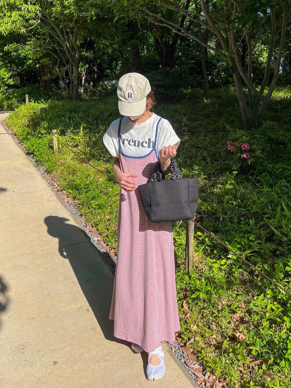 ピンク系のワンピース、ホワイト系のTシャツ/カットソー、ブラック系のトートバッグを着用したレディースの春コーディネートの2枚目の写真