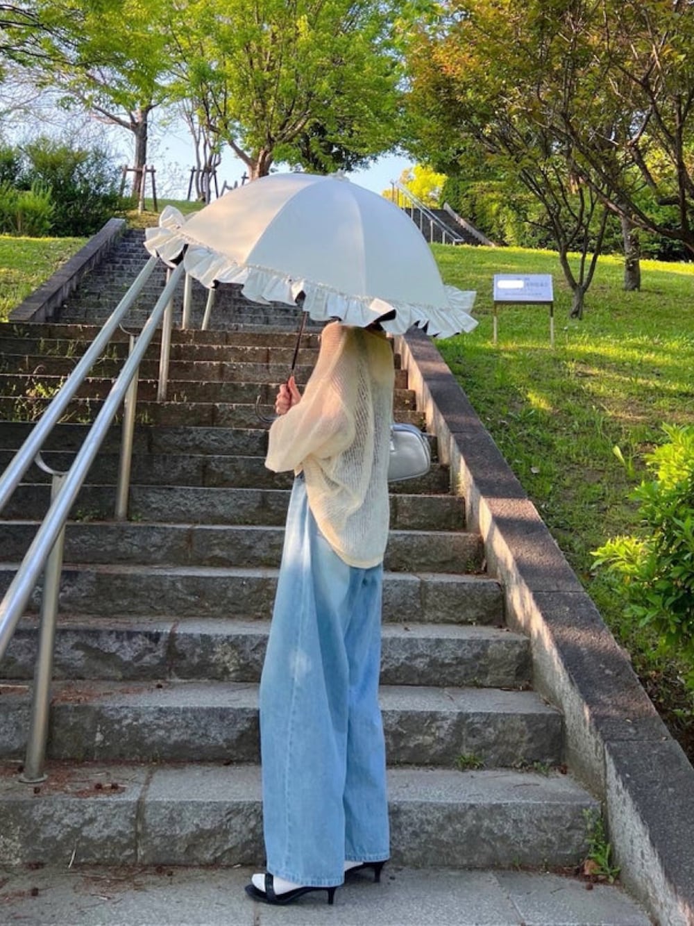 ホワイト系のニット/セーター、ブラック系のタンクトップ、ブルー系のデニムパンツを着用したレディースの冬コーディネートの2枚目の写真