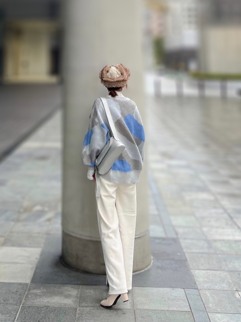 グレー系のニット/セーター、ホワイト系のトップス、シルバー系のショルダーバッグを着用したレディースの冬コーディネートの3枚目の写真