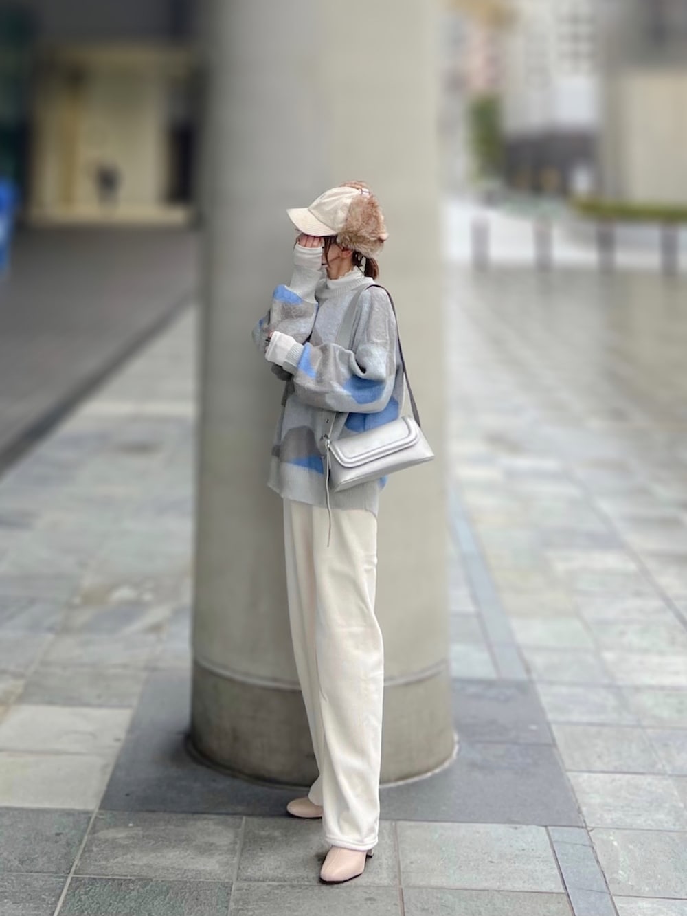 グレー系のニット/セーター、ホワイト系のトップス、シルバー系のショルダーバッグを着用したレディースの冬コーディネートの2枚目の写真