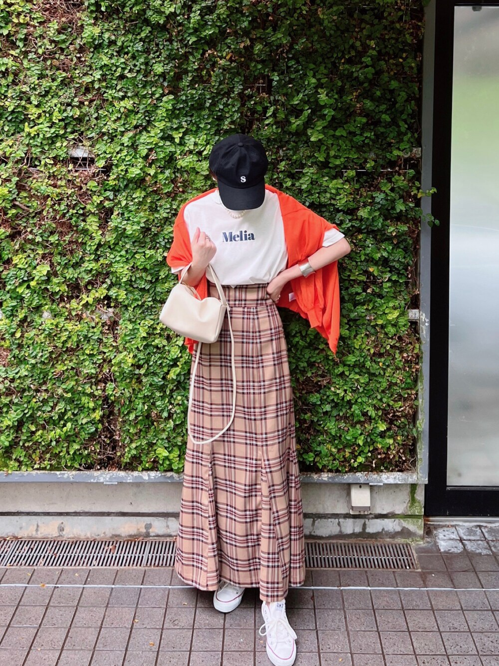 オレンジ系のカーディガン/ボレロ、ホワイト系のTシャツ/カットソー、ベージュ系のスカートを着用したレディースの春コーディネートの2枚目の写真