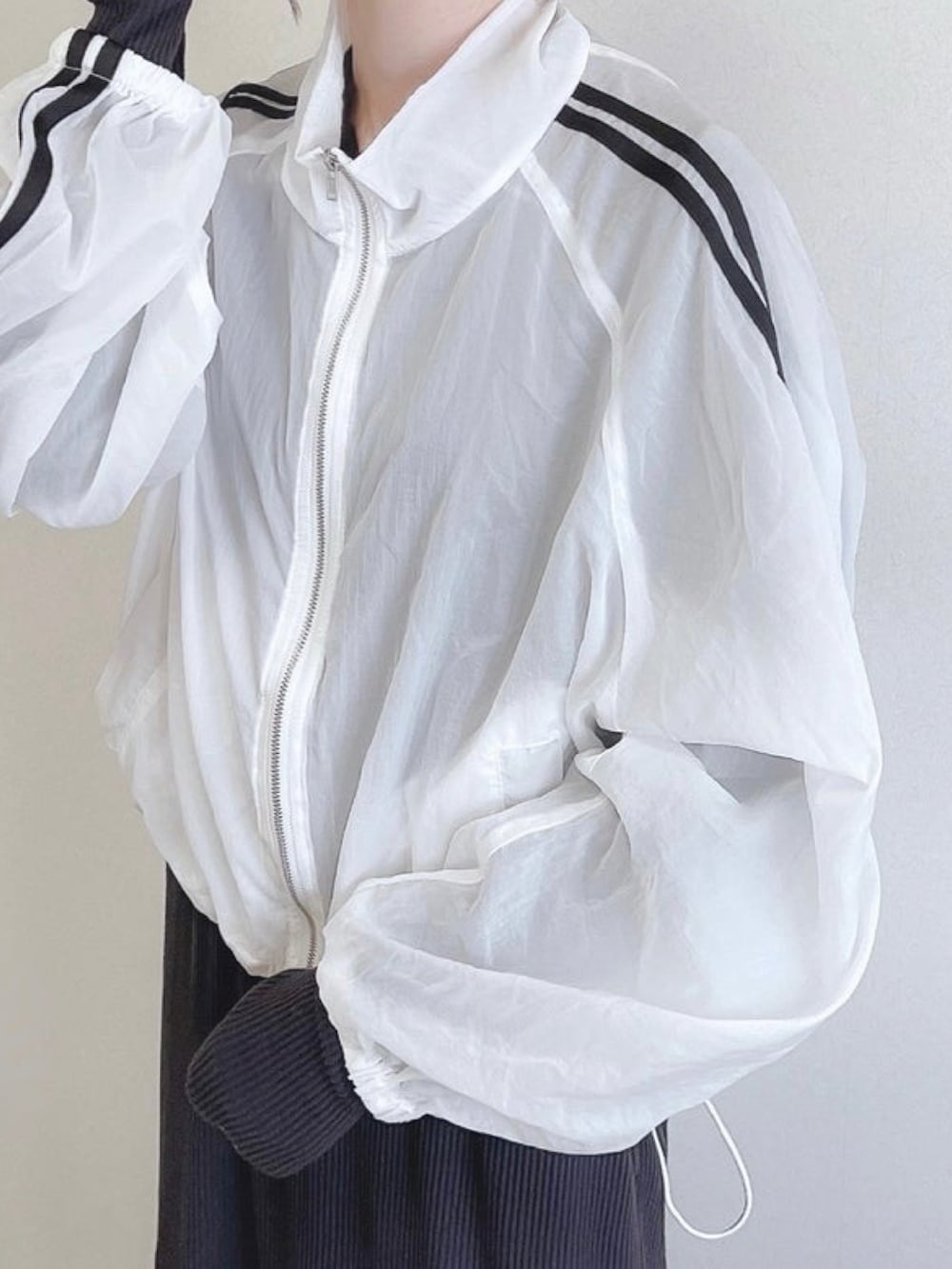 ホワイト系のナイロンジャケット、ブラック系のワンピース、ブラウン系のトートバッグを着用したレディースの冬コーディネートの2枚目の写真