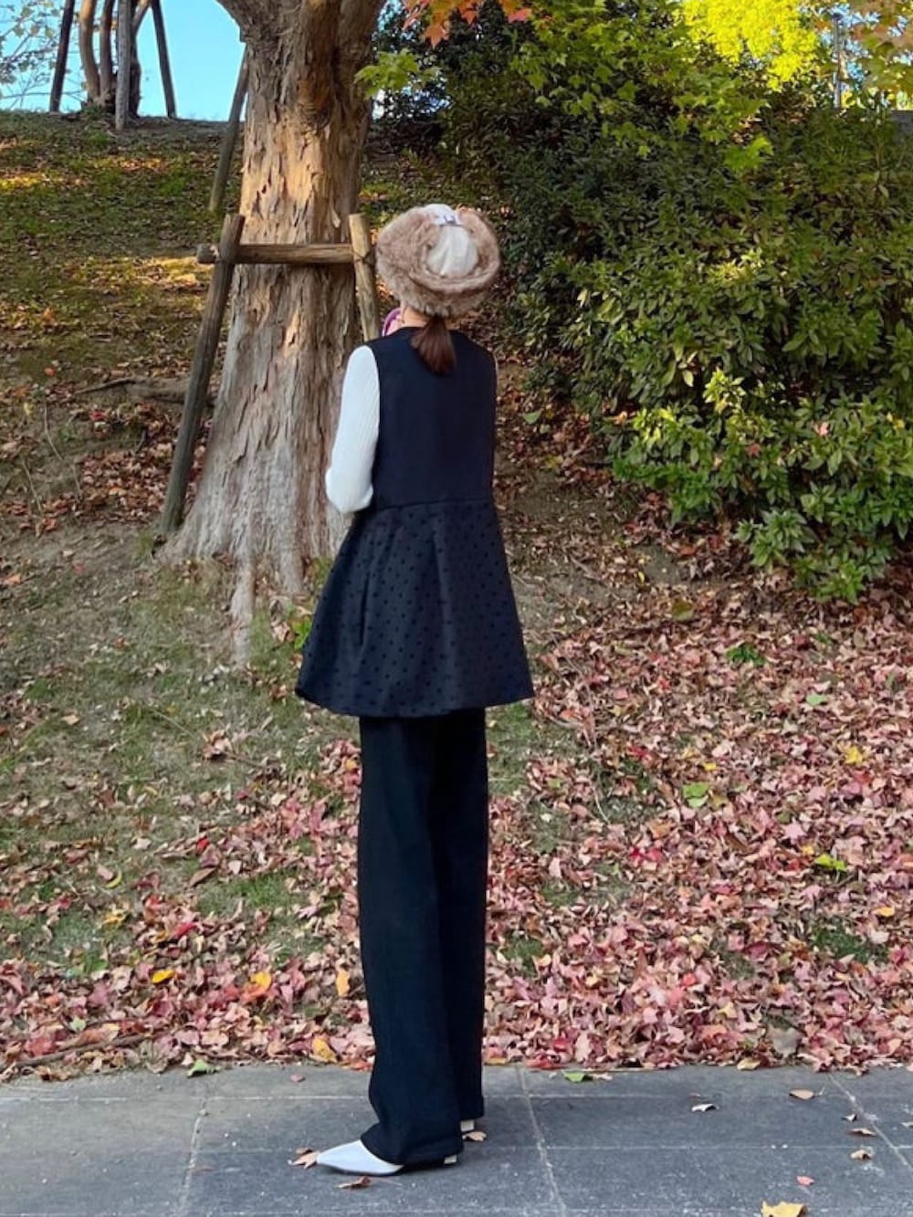 ホワイト系のニット/セーター、ブラック系のベスト、ブラック系のその他パンツを着用したレディースの秋コーディネートの2枚目の写真