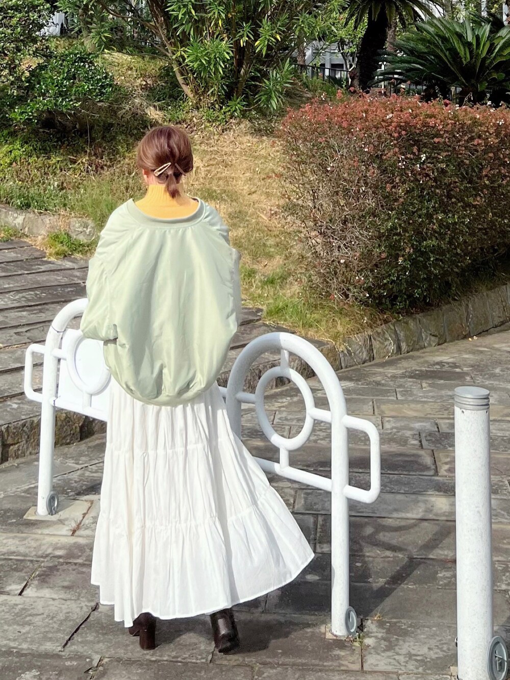 グリーン系のMA-1、イエロー系のニット/セーター、ホワイト系のスカートを着用したレディースの秋コーディネートの2枚目の写真