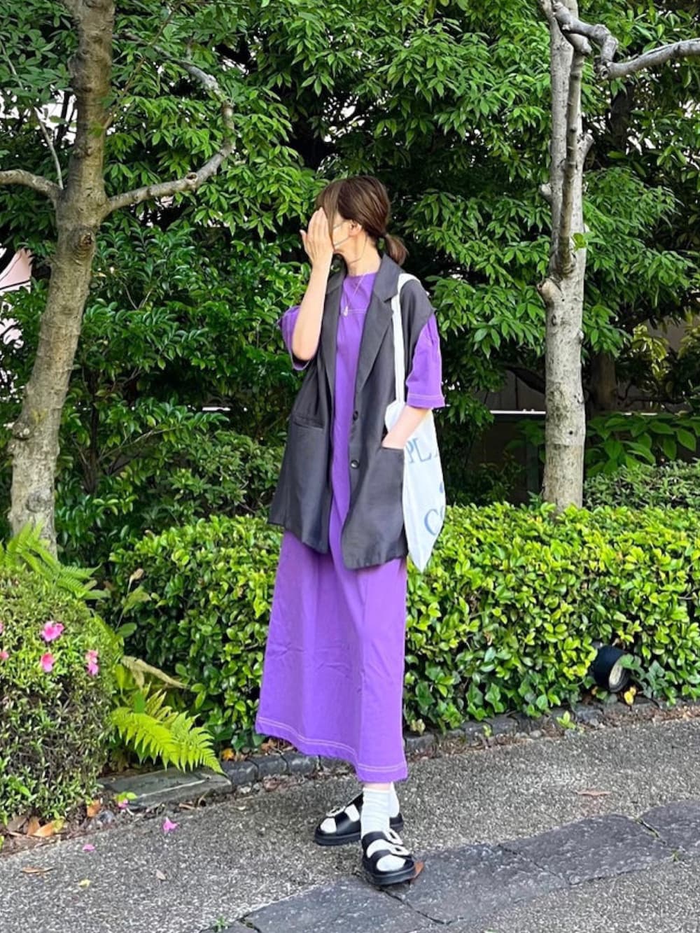 パープル系のワンピース、ブラック系のサンダル、グレー系のベストを着用したレディースの夏コーディネートの2枚目の写真