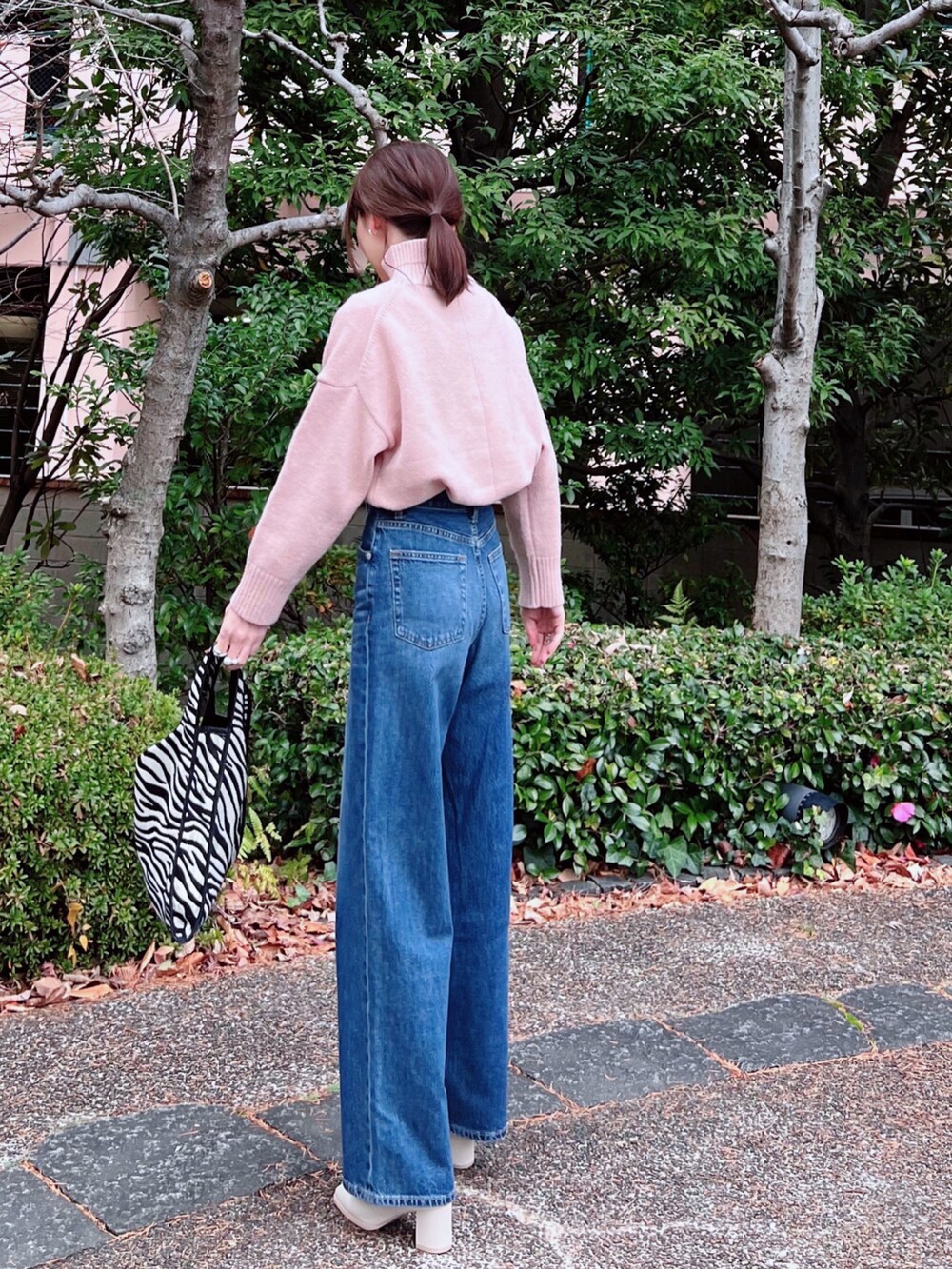 グレー系のノーカラーコート、ピンク系のニット/セーター、ブルー系のデニムパンツを着用したレディースの冬コーディネートの3枚目の写真