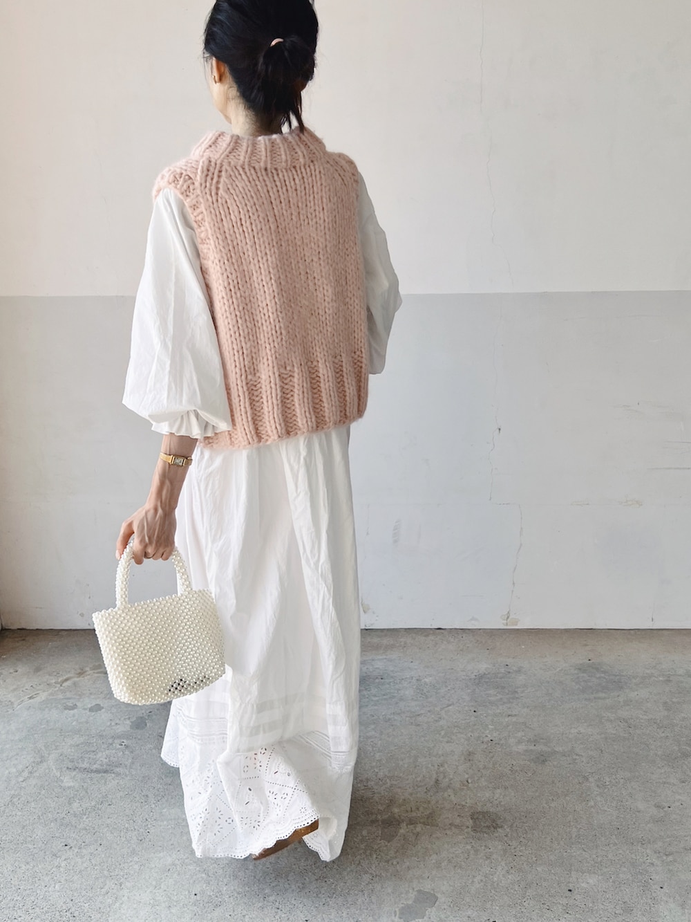 ピンク系のベスト、ホワイト系のワンピース、ホワイト系のハンドバッグを着用したレディースの春コーディネートの3枚目の写真