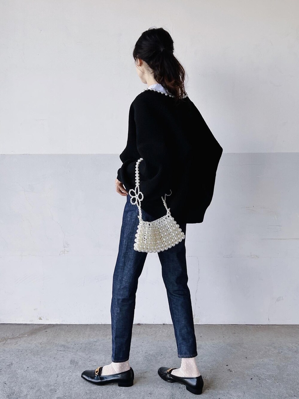 ホワイト系のTシャツ/カットソー、ブラック系のカーディガン/ボレロ、ブルー系のデニムパンツを着用したレディースの秋コーディネートの3枚目の写真