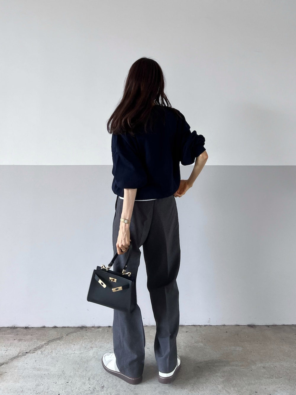 ブルー系のスウェット、ブラック系のショルダーバッグ、グレー系のスラックスを着用したレディースの秋コーディネートの3枚目の写真