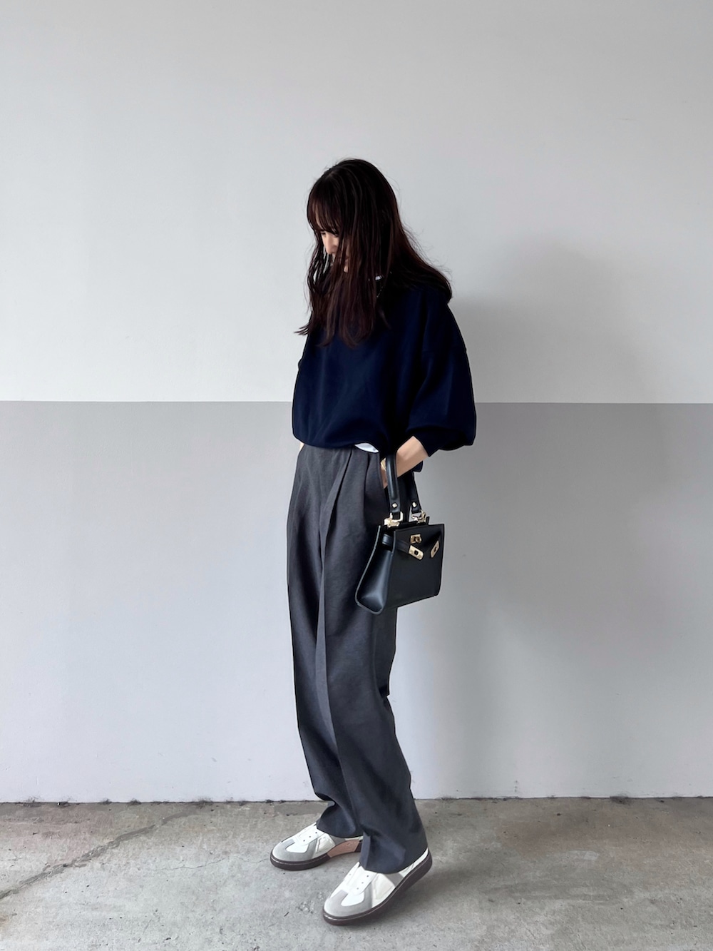 ブルー系のスウェット、ブラック系のショルダーバッグ、グレー系のスラックスを着用したレディースの秋コーディネートの4枚目の写真