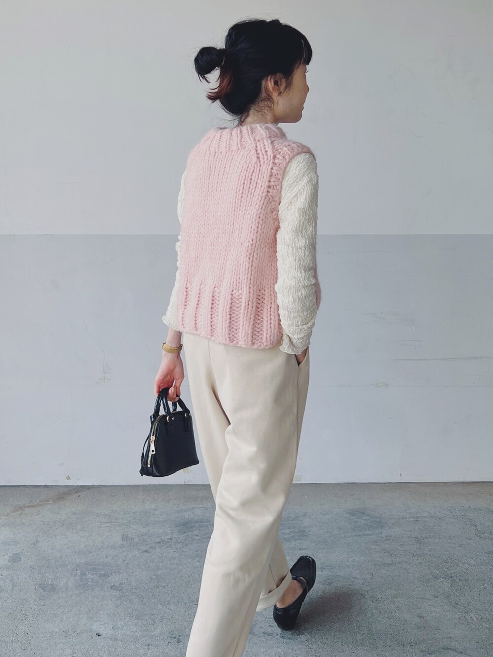 ピンク系のベスト、ブラック系のショルダーバッグ、ベージュ系のパンツを着用したレディースの春コーディネートの3枚目の写真