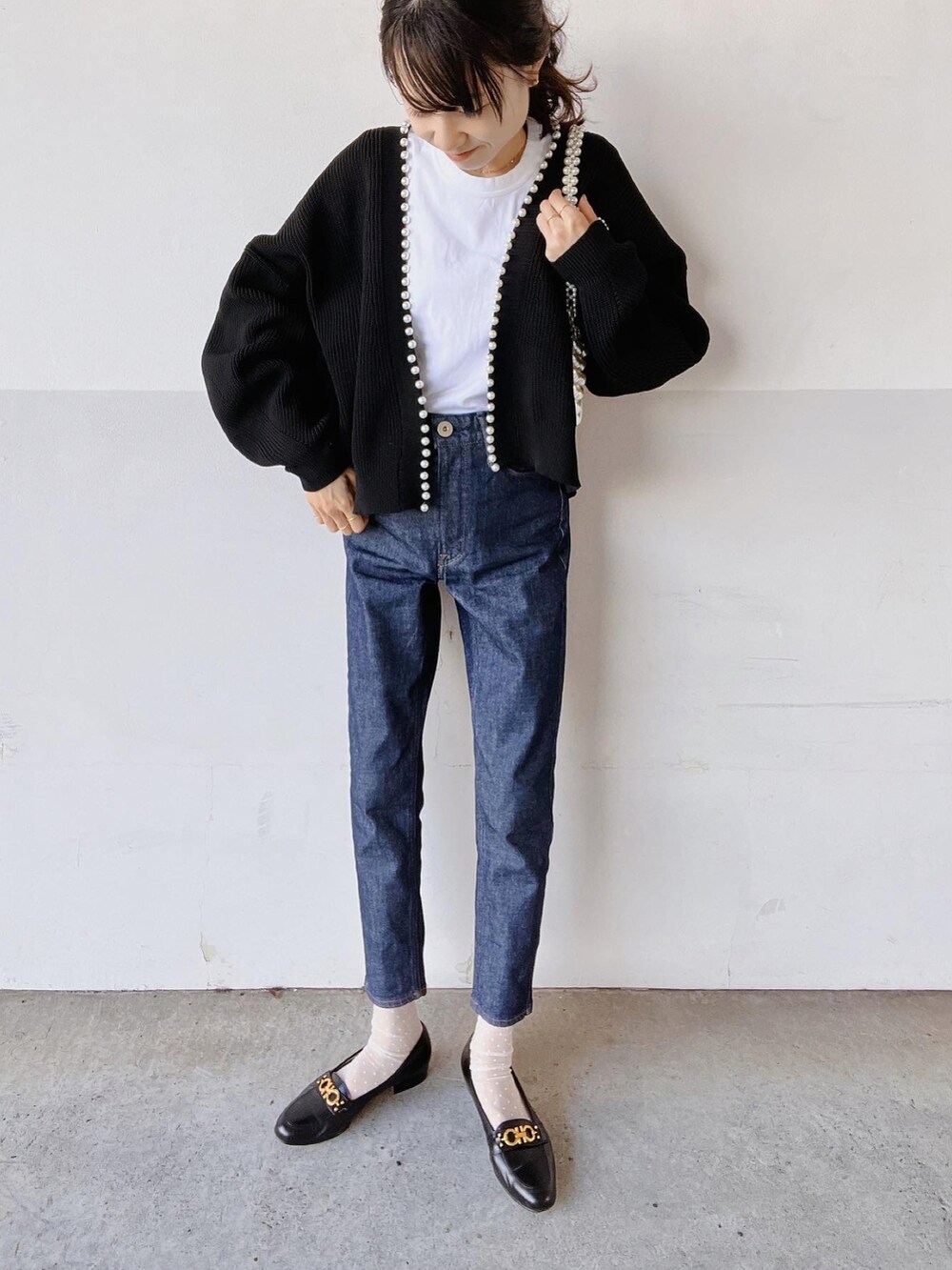 ホワイト系のTシャツ/カットソー、ブラック系のカーディガン/ボレロ、ブルー系のデニムパンツを着用したレディースの秋コーディネートの2枚目の写真