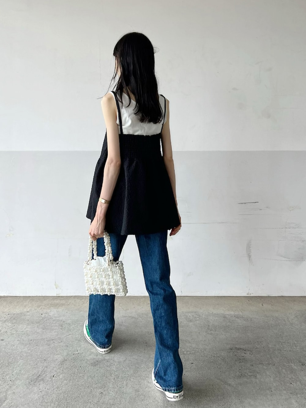 ブラック系のワンピース、ブルー系のデニムパンツ、ホワイト系のトートバッグを着用したレディースの秋コーディネートの3枚目の写真