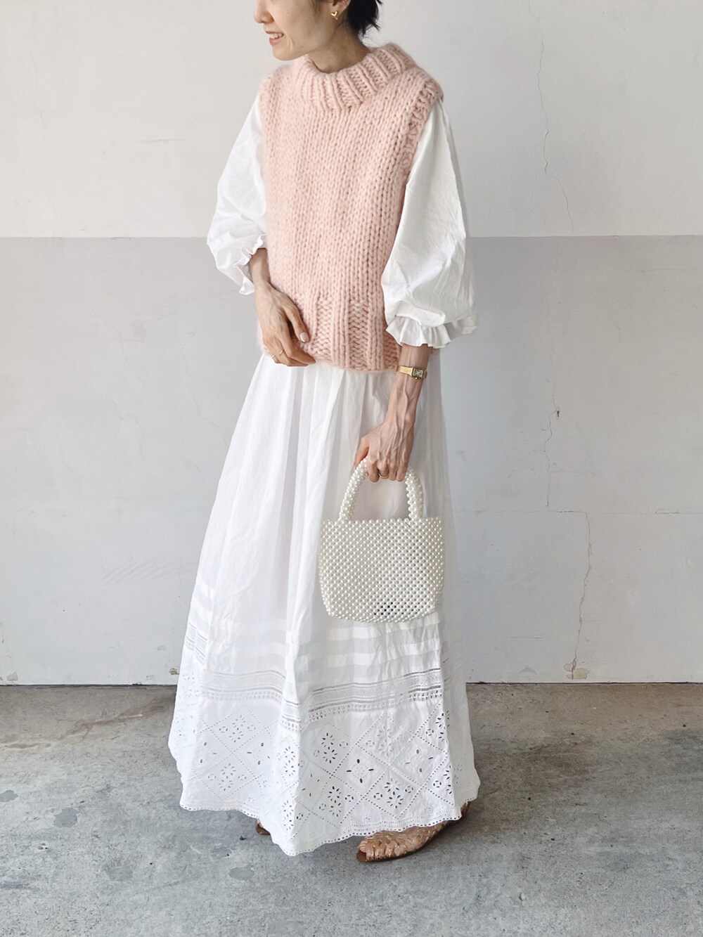 ピンク系のベスト、ホワイト系のワンピース、ホワイト系のハンドバッグを着用したレディースの春コーディネートの2枚目の写真