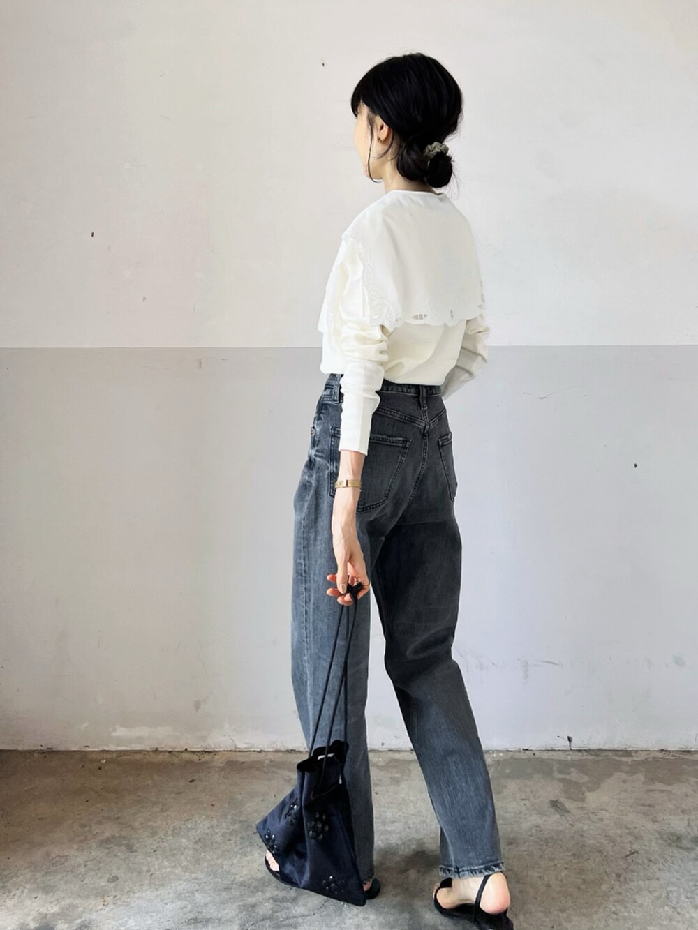 ホワイト系のTシャツ/カットソー、ブラック系のハンドバッグ、グレー系のデニムパンツを着用したレディースの秋コーディネートの2枚目の写真