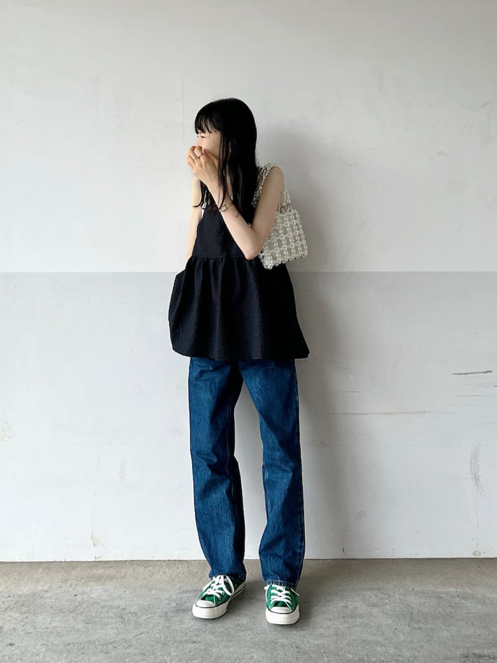 ブラック系のワンピース、ブルー系のデニムパンツ、ホワイト系のトートバッグを着用したレディースの秋コーディネートの2枚目の写真