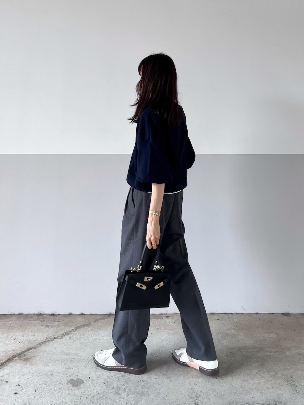 ブルー系のスウェット、ブラック系のショルダーバッグ、グレー系のスラックスを着用したレディースの秋コーディネートの2枚目の写真