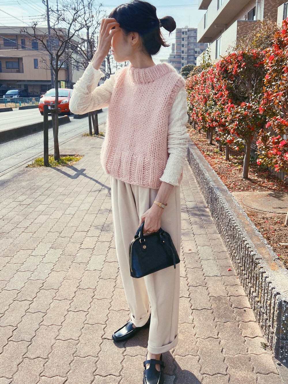 ピンク系のベスト、ブラック系のショルダーバッグ、ベージュ系のパンツを着用したレディースの春コーディネートの4枚目の写真